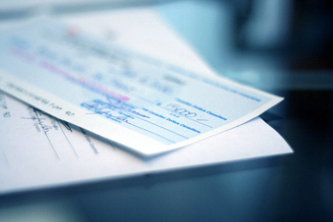 blue-tinted photo showing a close-up of a check, made out for15,000 dollars.