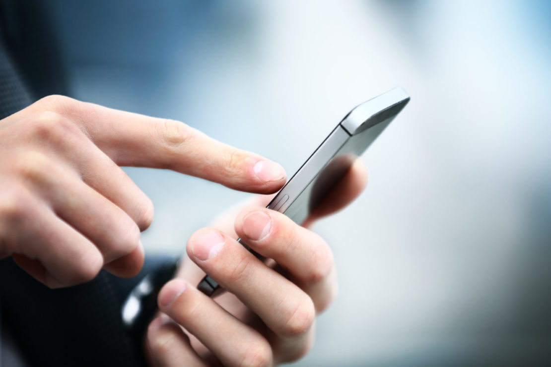 close up of a man's finger touching an extremely thin mobile phone. 