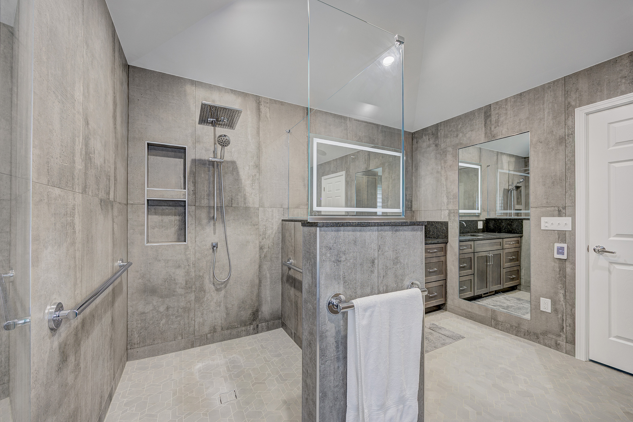 Luxury bathroom remodel in Troy, Michigan featuring large format tile walls, a custom curb shower, and built-in storage niches.