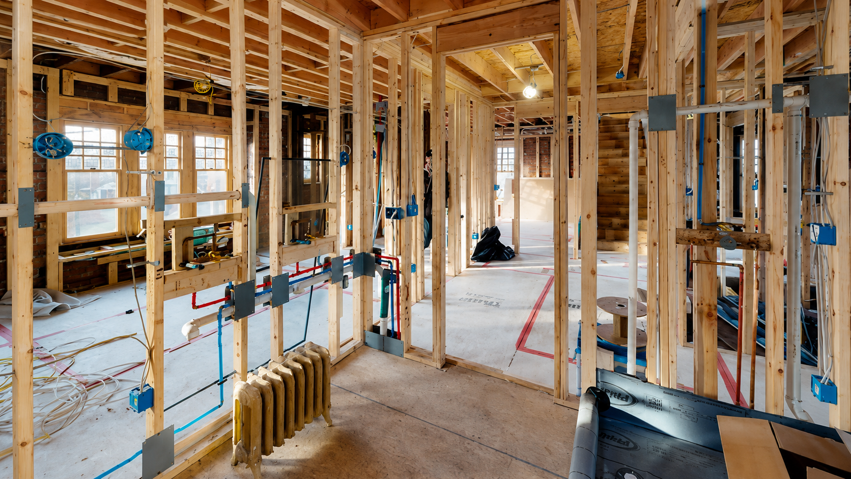 New framing, electrical wiring, plumbing rough-ins, and an original steam radiator during the complete renovation of a 1906 Detroit Tudor by Maxwell Building Services.