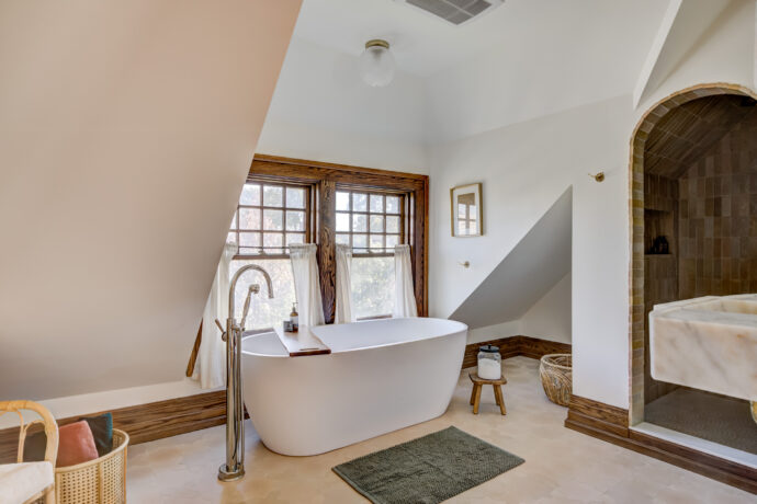 Luxury primary bathroom remodel in Birmingham, Michigan featuring handcrafted Zia clay tile, a freestanding soaking tub, imported Turkish marble sink, Waterworks unlacquered brass fixtures, Star & Cross porcelain floor tile, and a frameless glass shower.