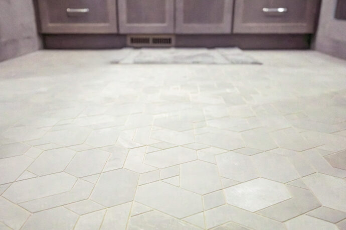 Luxury bathroom floor featuring Atlas Concorde Boost Grey mosaic porcelain tile in a geometric pattern with custom Cannon Gray maple vanity in Troy, Michigan.