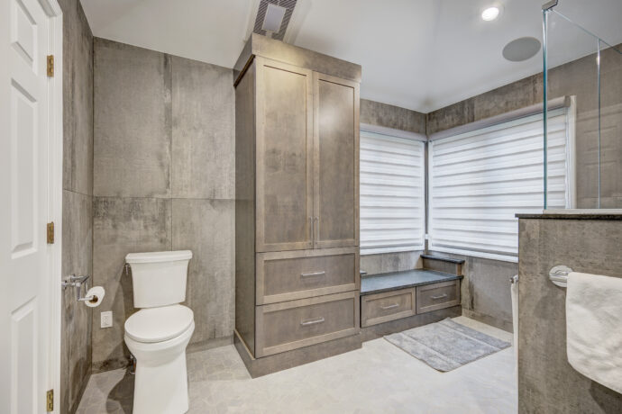 Luxury primary bathroom in Troy featuring custom Cannon Gray maple linen cabinetry, built-in window bench, Industrial Gray porcelain tile, and mosaic porcelain flooring.