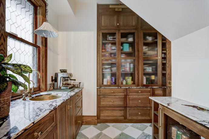 Luxury butler's pantry with Dura Supreme inset cabinetry, marble countertops, green and white checkered marble flooring, fluted glass cabinets, and unlacquered brass fixtures in a Birmingham, Michigan home.