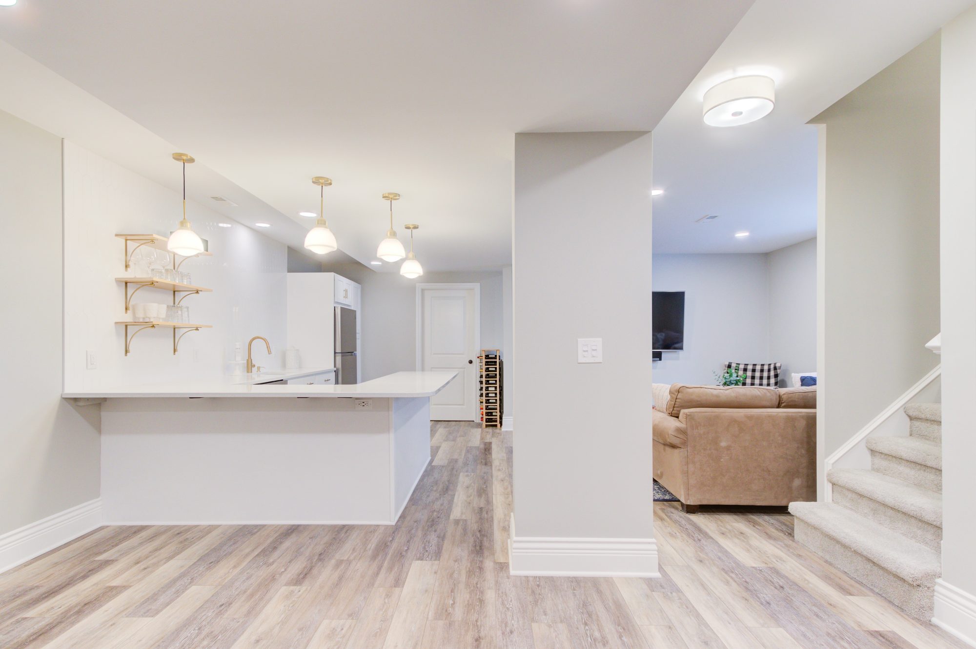 Finished basement in Birmingham MI with a full kitchenette, quartz counters and an open lounge beyond
