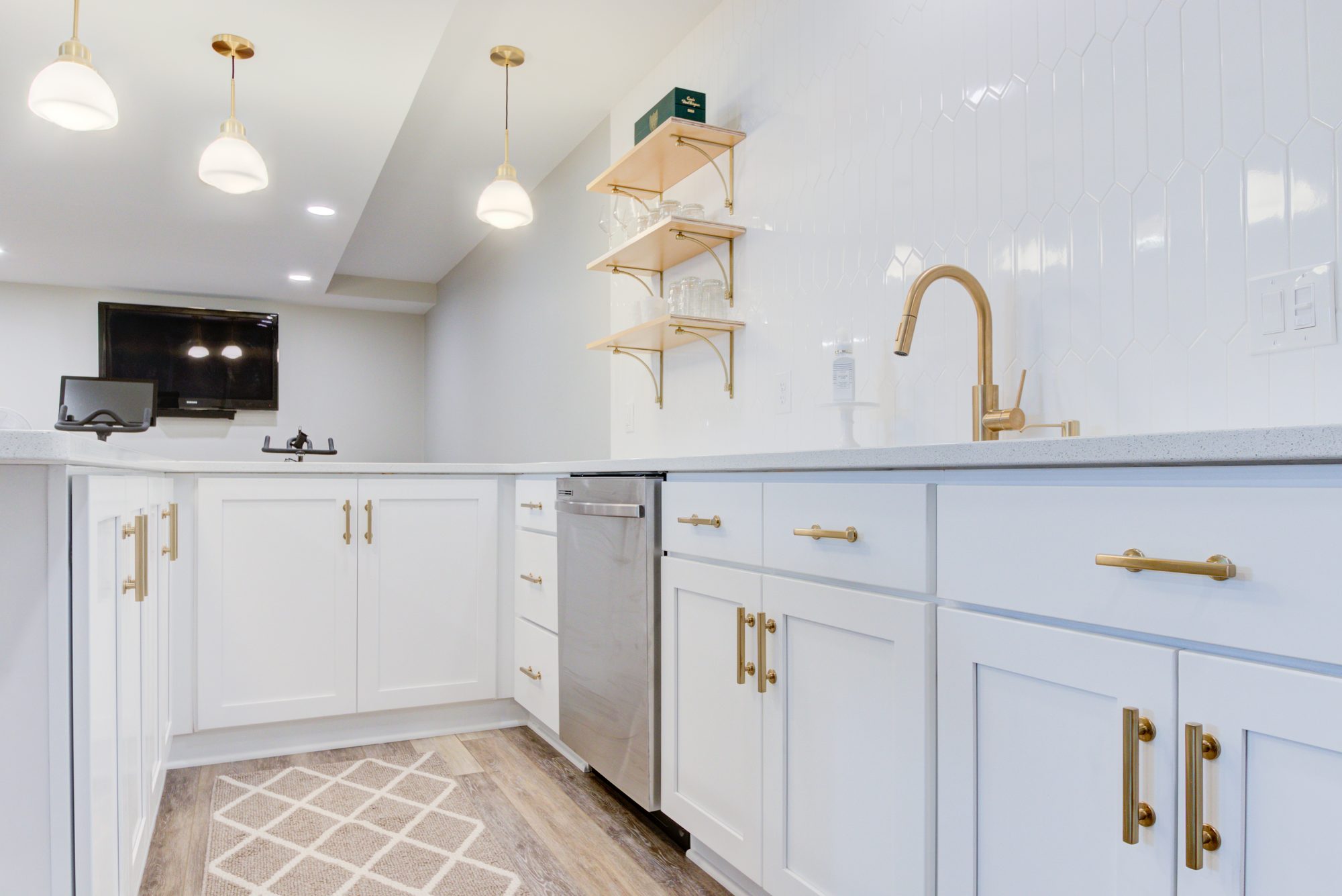 Wet bar cabinet run with a built in dishwasher, quartz counters and brass hardware in a Birmingham MI basement
