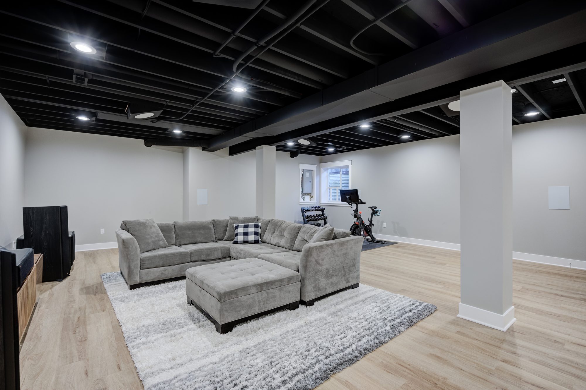 Sectional seating below a black painted exposed joist ceiling in a Royal Oak MI basement remodel