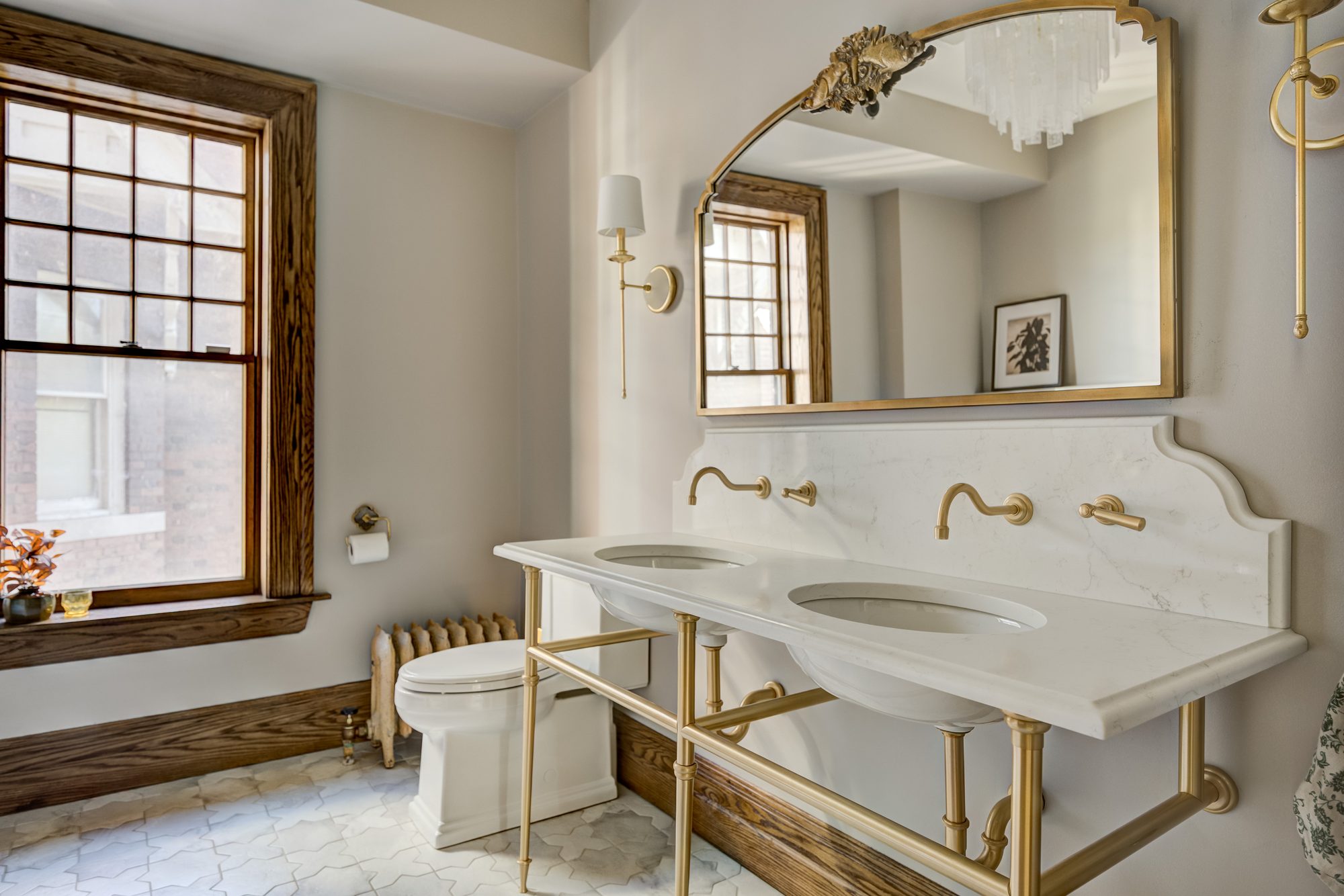 Marble vanity top with a shaped backsplash and wall mount brass faucets in a Birmingham MI bathroom remodel