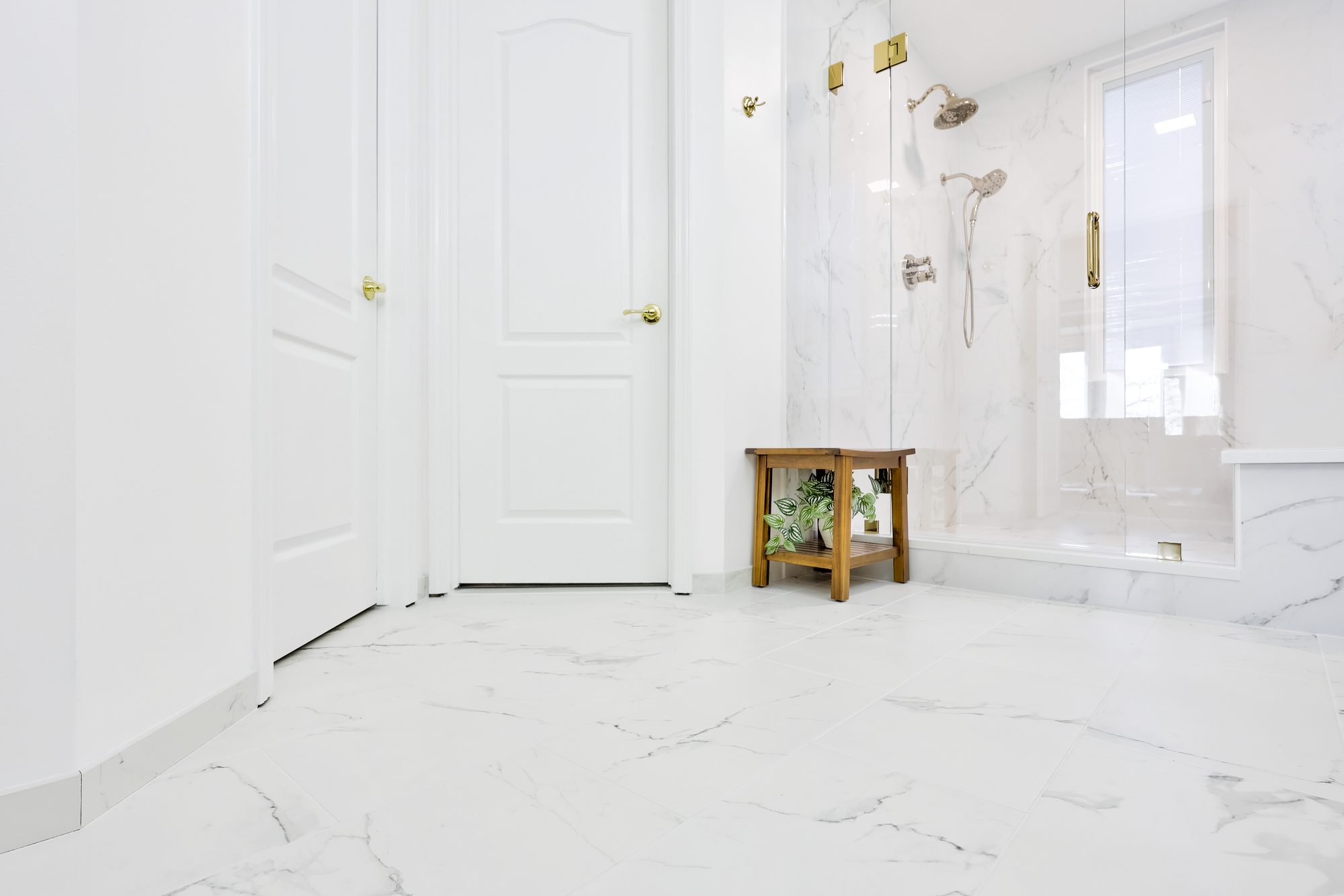 Large format marble look porcelain floor tile running toward the closet doors in a Birmingham MI bathroom