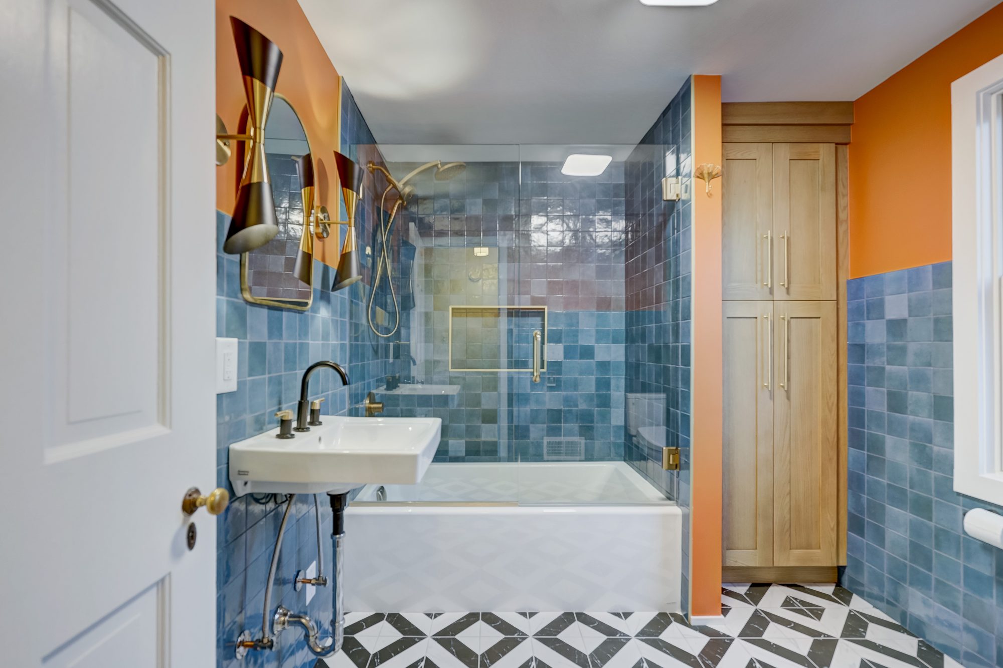 Remodeled bathroom in Ferndale MI with blue zellige tile, a terracotta accent wall and a black and white geometric tile floor