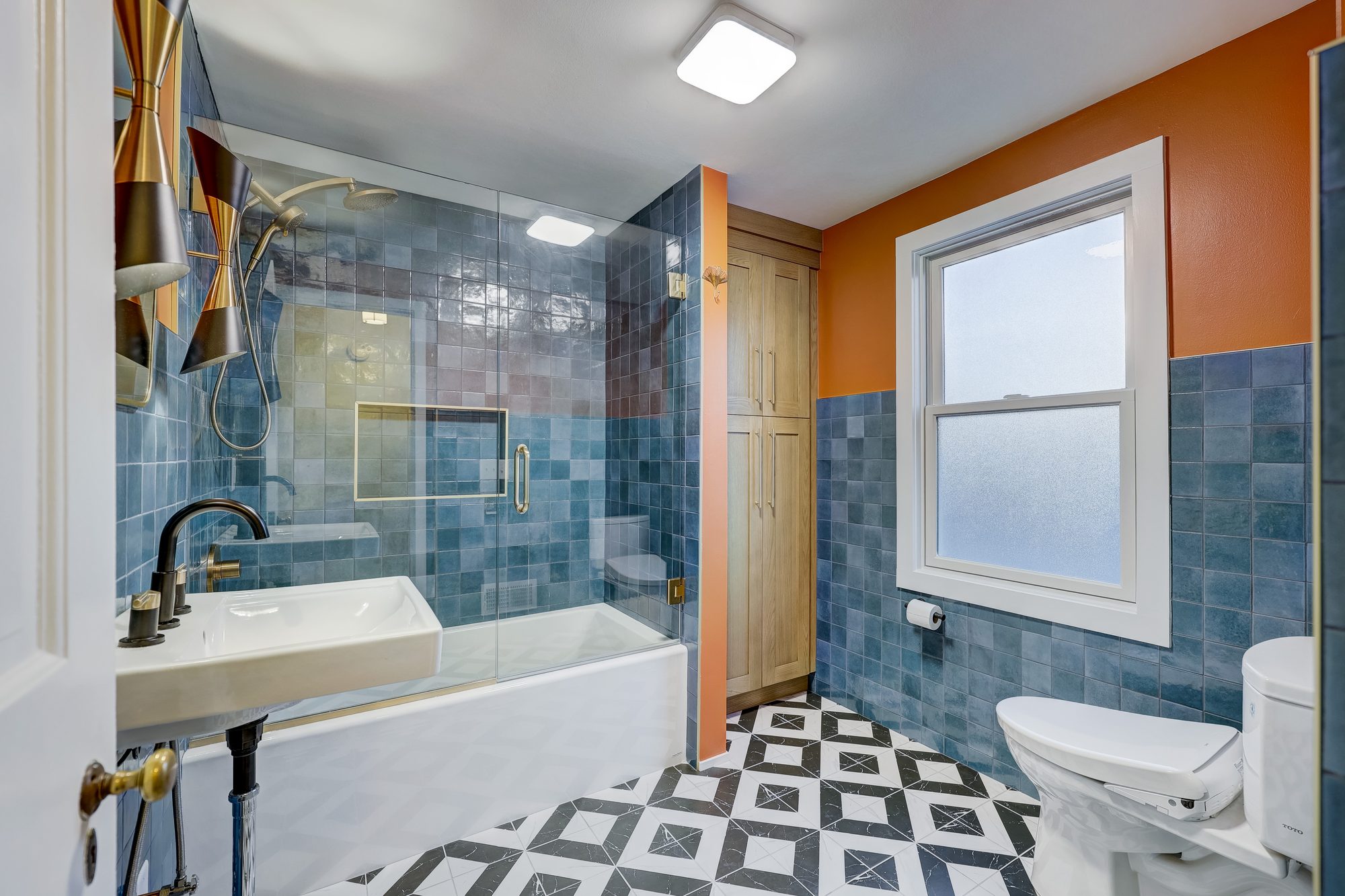 View from the doorway to the alcove tub and built in white oak linen tower in a Ferndale MI bathroom remodel