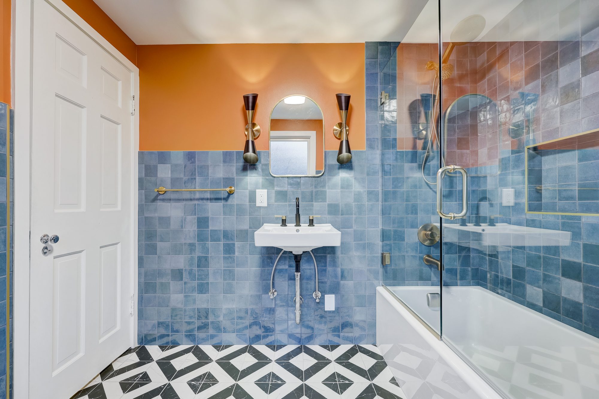 Sink wall with an arched brass mirror and mid century brass sconces in a Ferndale MI bathroom remodel