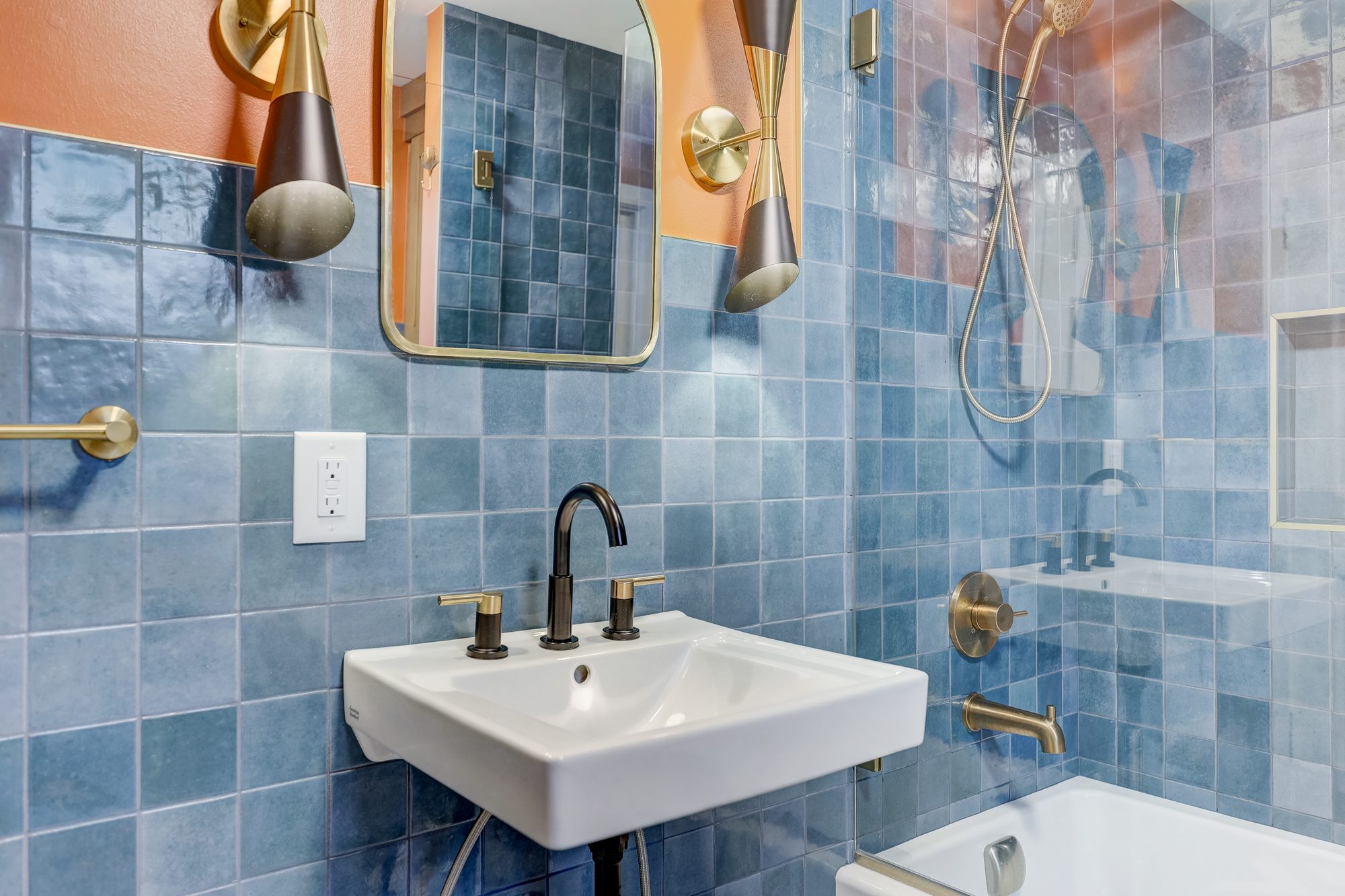 Wall mount sink with a black and brass faucet against blue zellige tile in a Ferndale MI bathroom