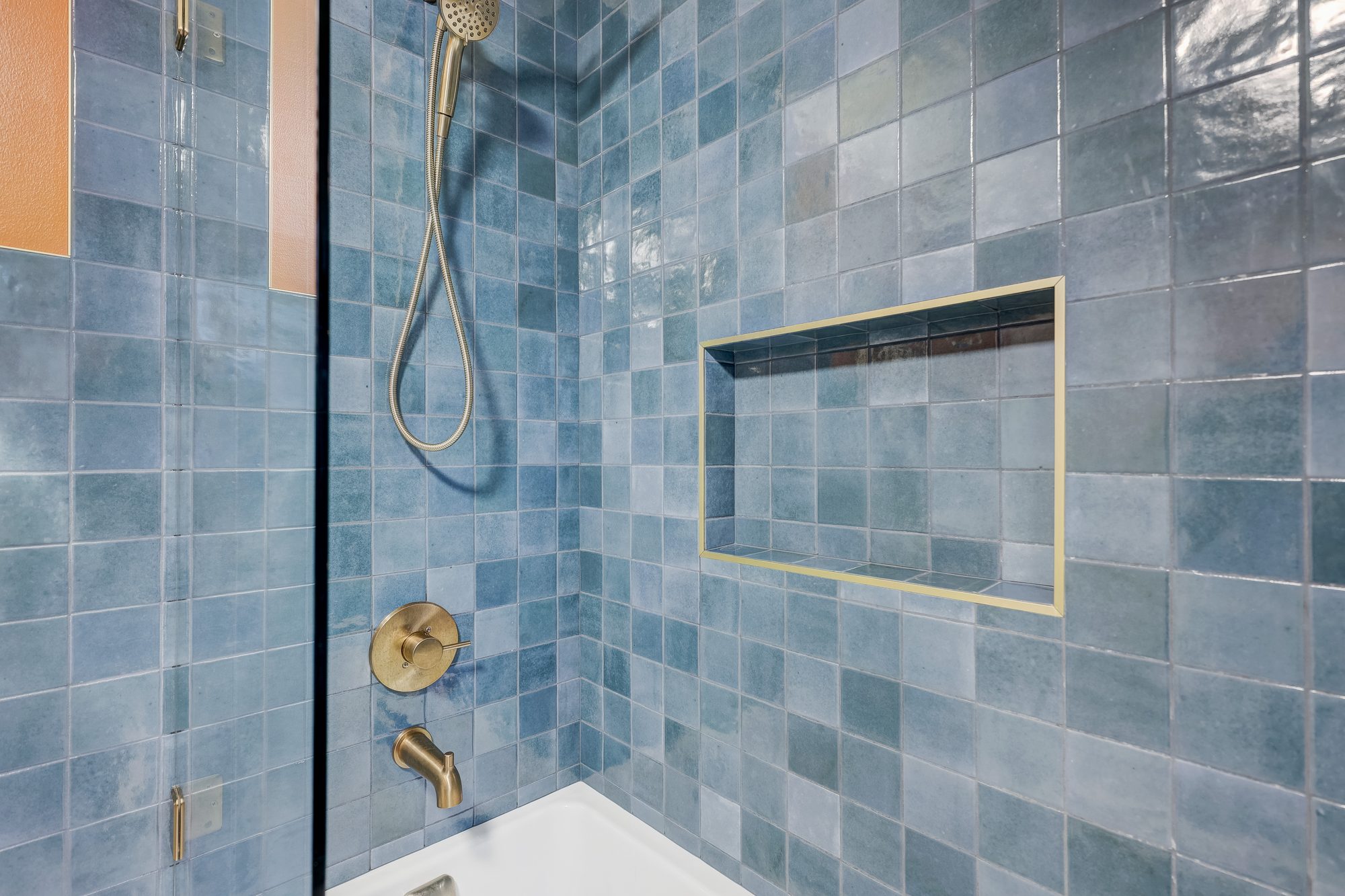 Brass tub filler, shower valve and hand shower in a blue zellige tile surround in a Ferndale MI bathroom