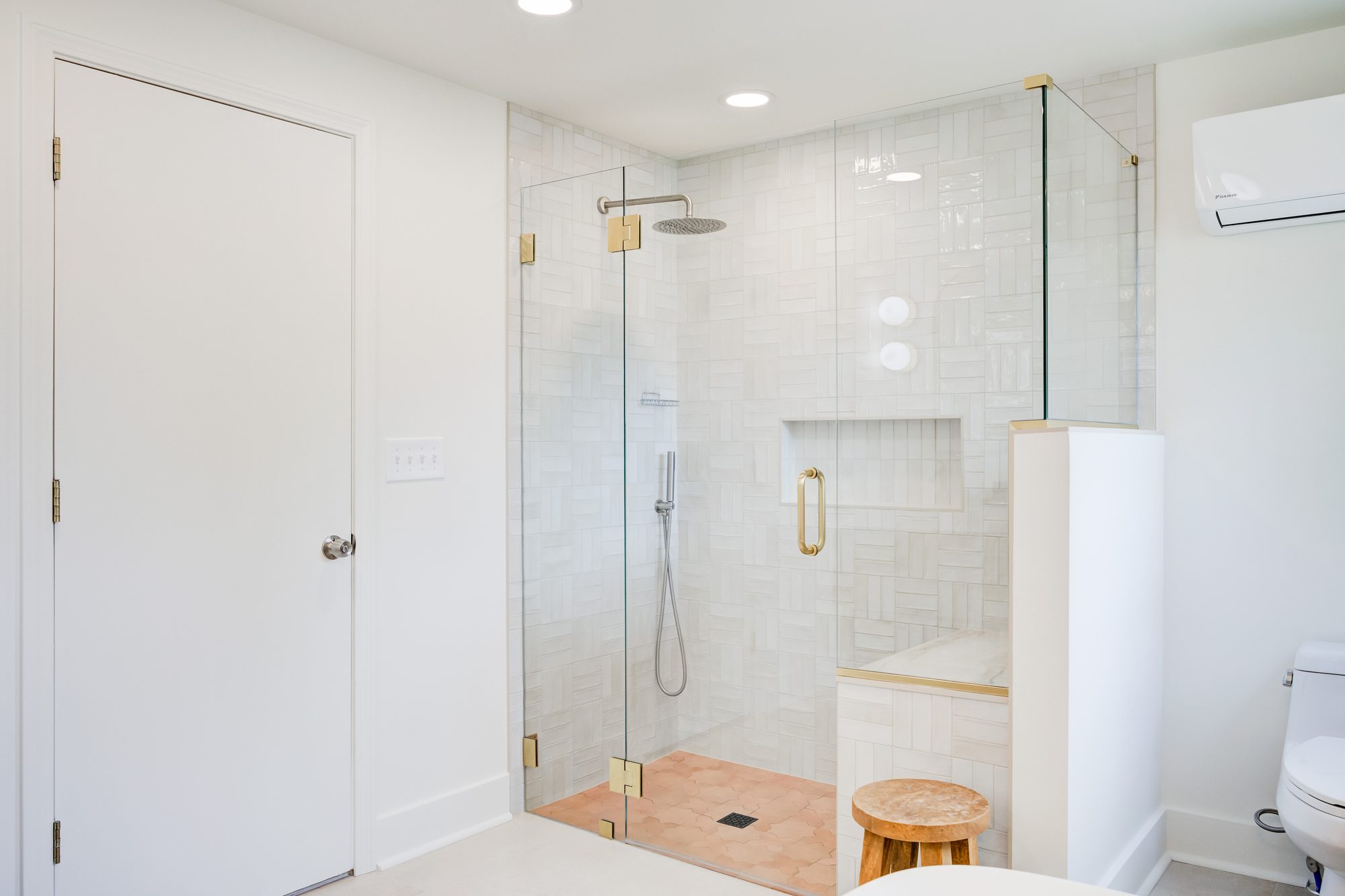 Frameless glass shower with brass hardware and handmade white wall tile in a Huntington Woods MI bathroom remodel