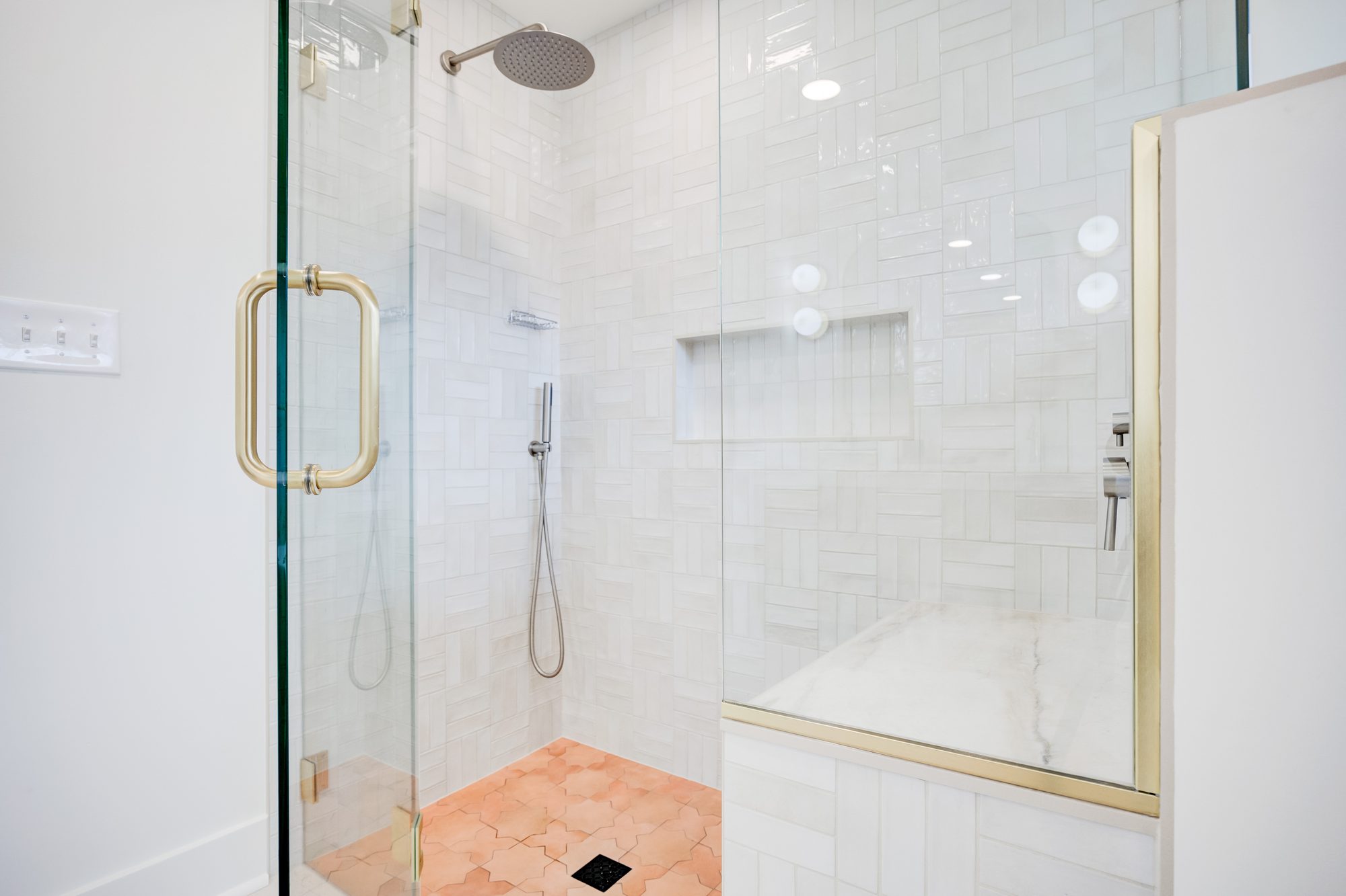 Shower interior with a rain head, hand shower, built in niche and marble bench in a Huntington Woods MI bathroom