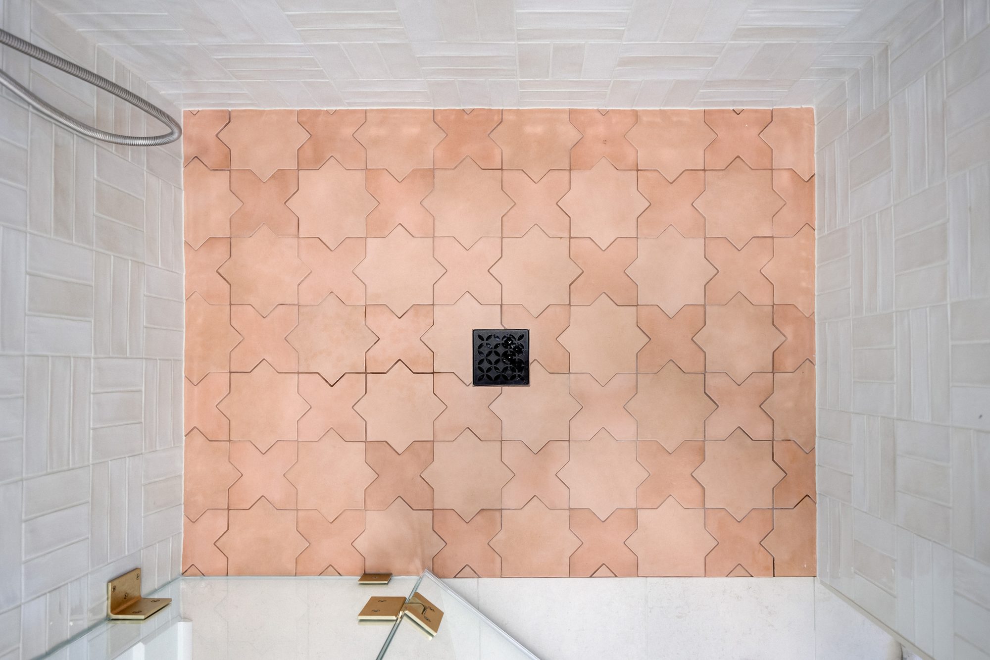 Terracotta star and cross tile shower floor set against handmade white wall tile in Huntington Woods MI