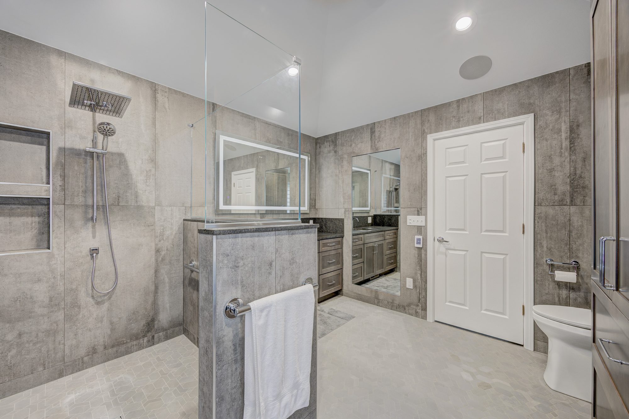 Curbless walk in shower with a tiled half wall and glass panel in a Troy MI bathroom remodel