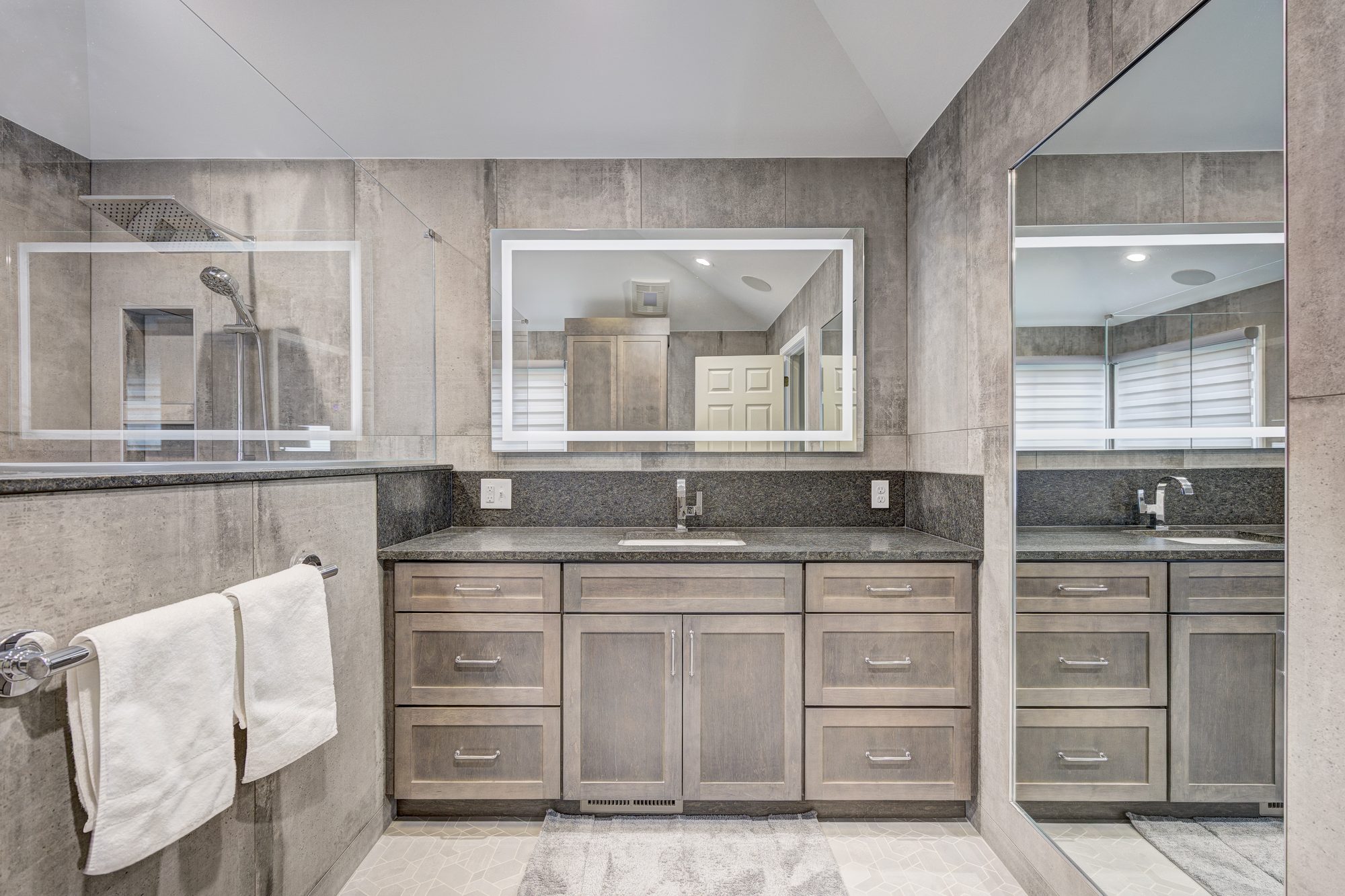 Vanity with a granite counter, full height granite backsplash and backlit LED mirror in a Troy MI bathroom