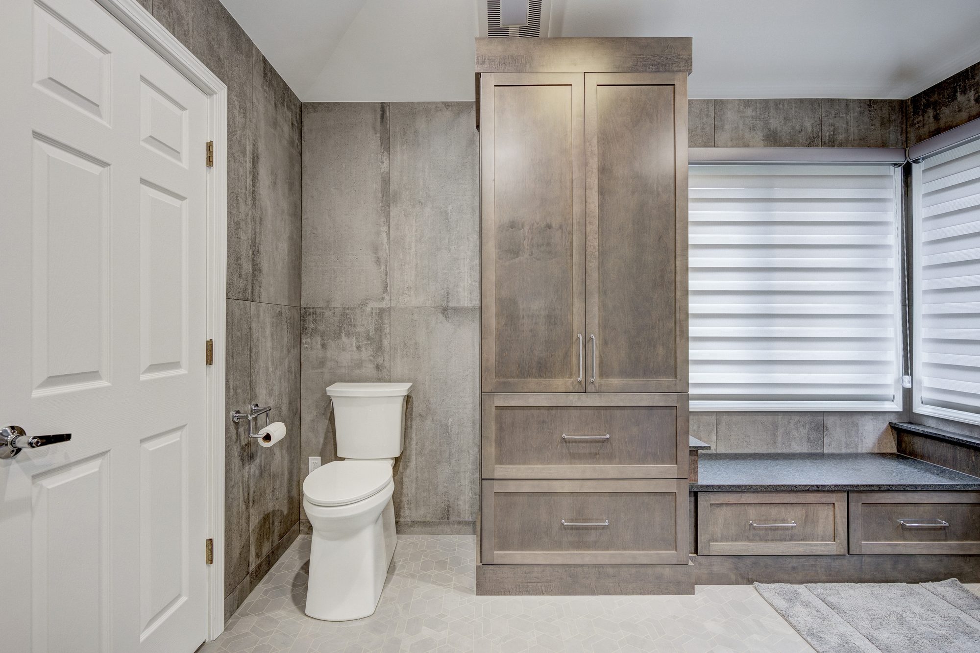 Built in linen tower beside a window bench with drawer storage in a Troy MI bathroom remodel