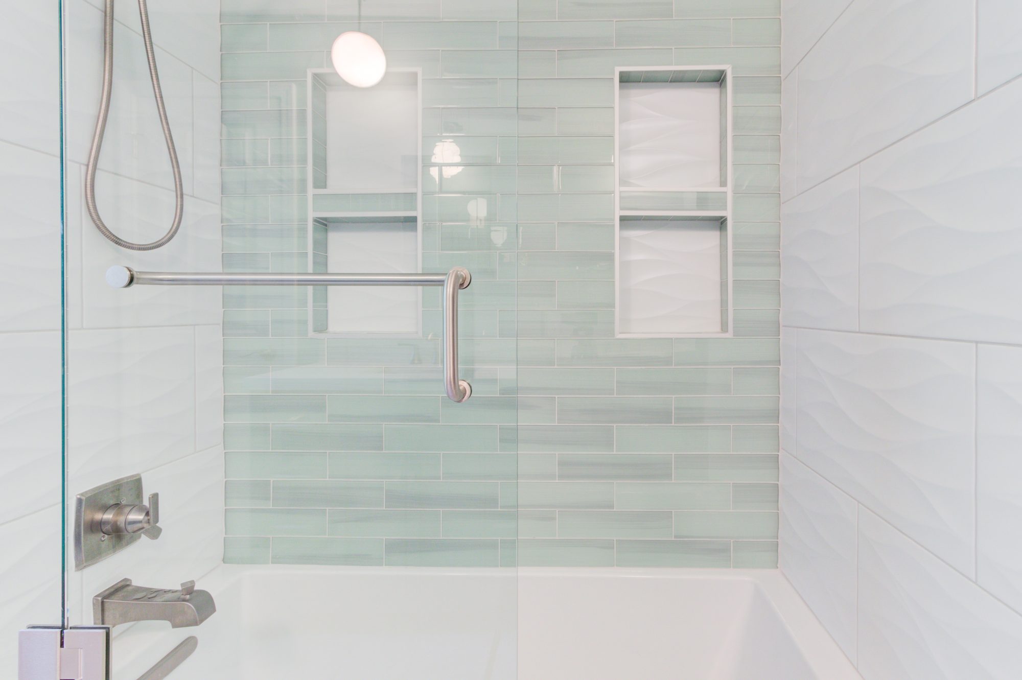Sea glass tile surround with two built in niches and a grab bar in a Troy MI bathroom remodel