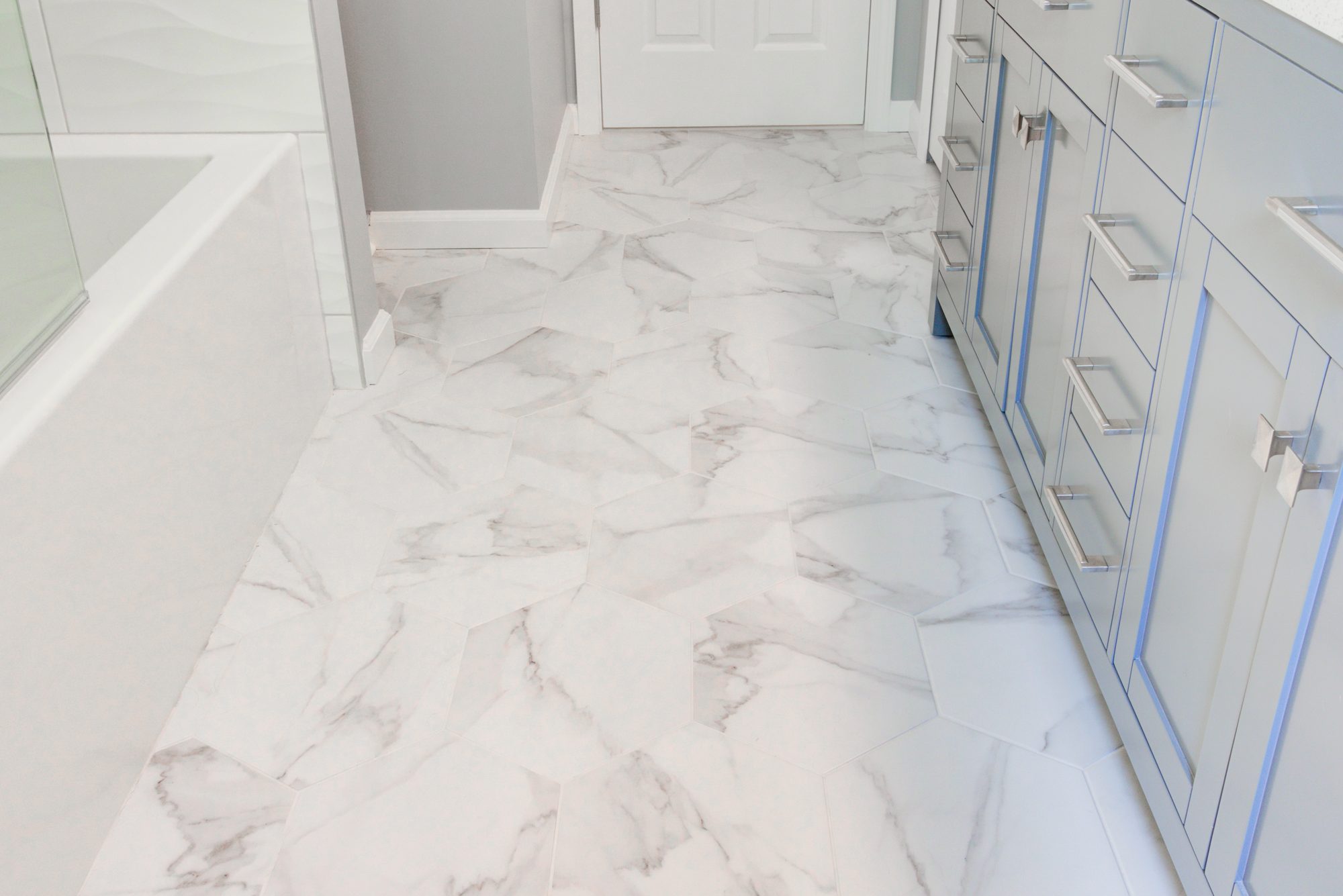 Large format marble look hexagon floor tile running from the tub to the vanity in a Troy MI bathroom remodel