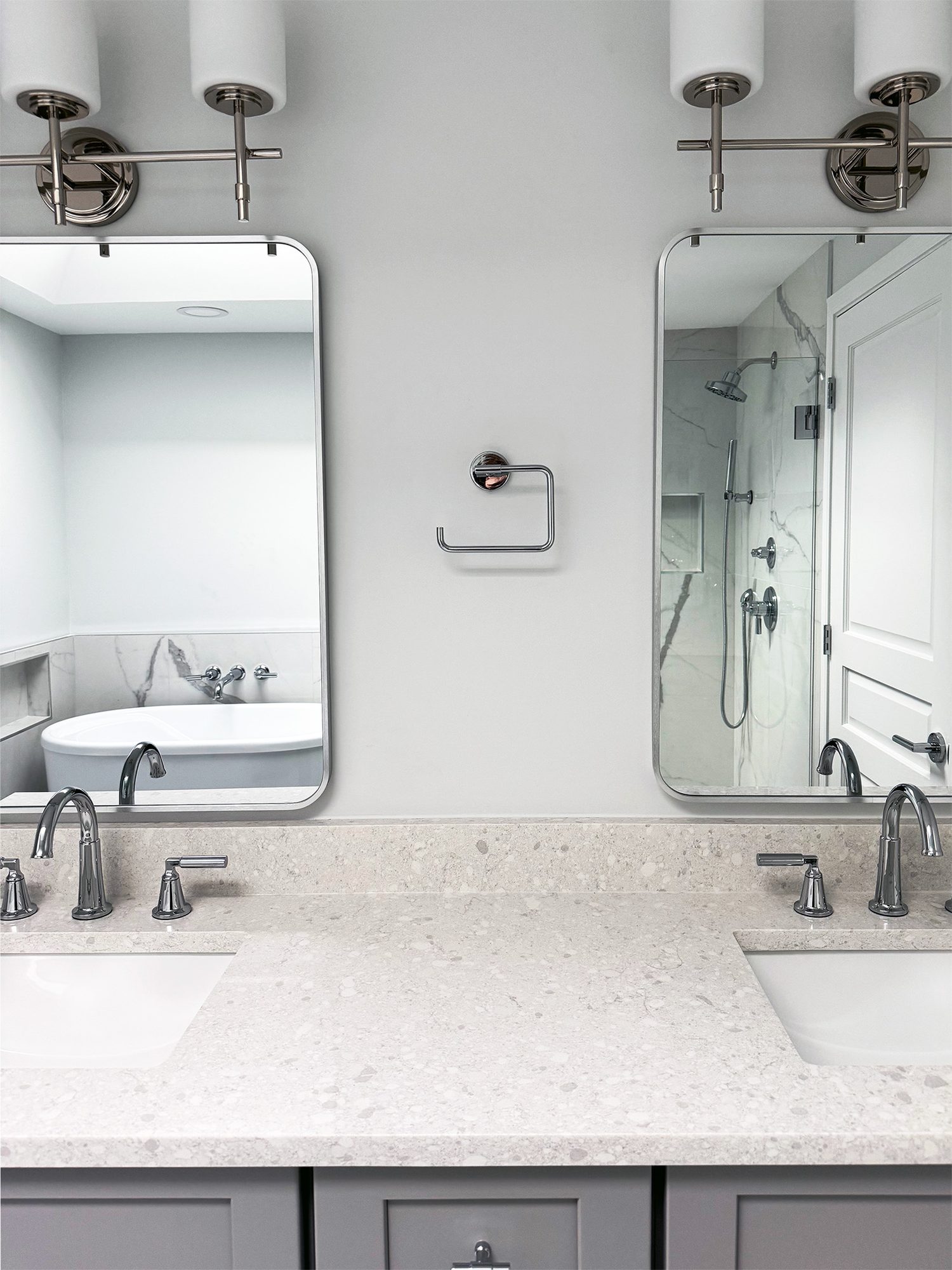 Double vanity with a quartz counter, twin rounded mirrors and chrome sconces in a Troy MI bathroom remodel