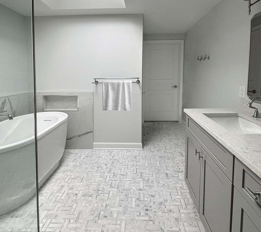 Troy MI bathroom remodel with a freestanding tub, marble herringbone floor and gray shaker vanity