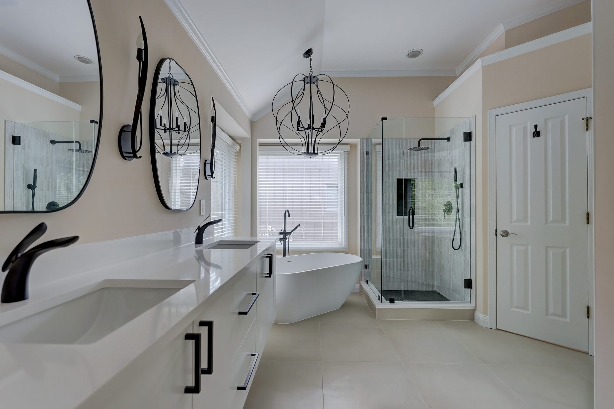 Remodeled primary bathroom in West Bloomfield MI with a freestanding soaking tub, floating double vanity and corner glass shower
