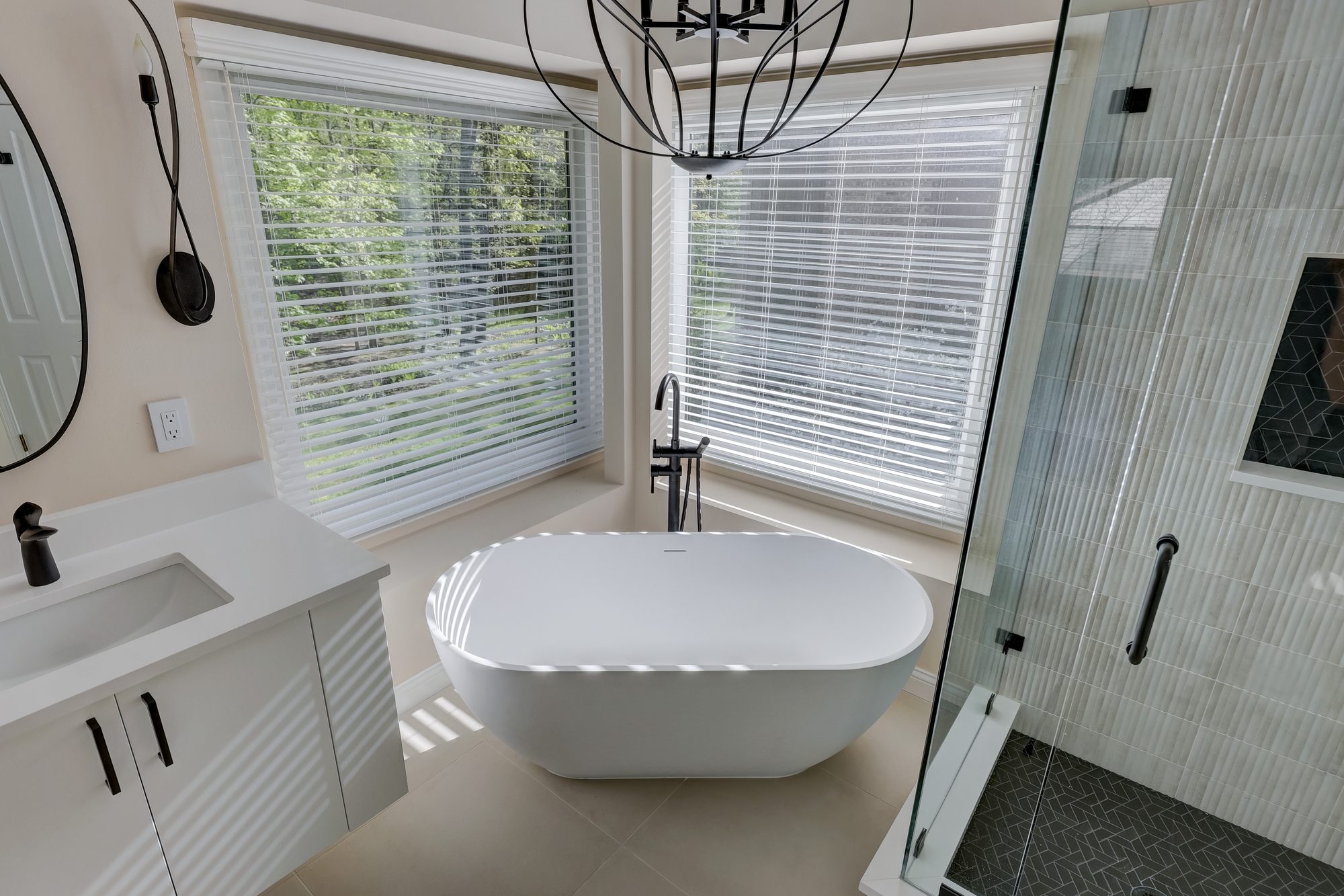 Freestanding soaking tub set into the bay window with a wooded view in a West Bloomfield MI bathroom remodel