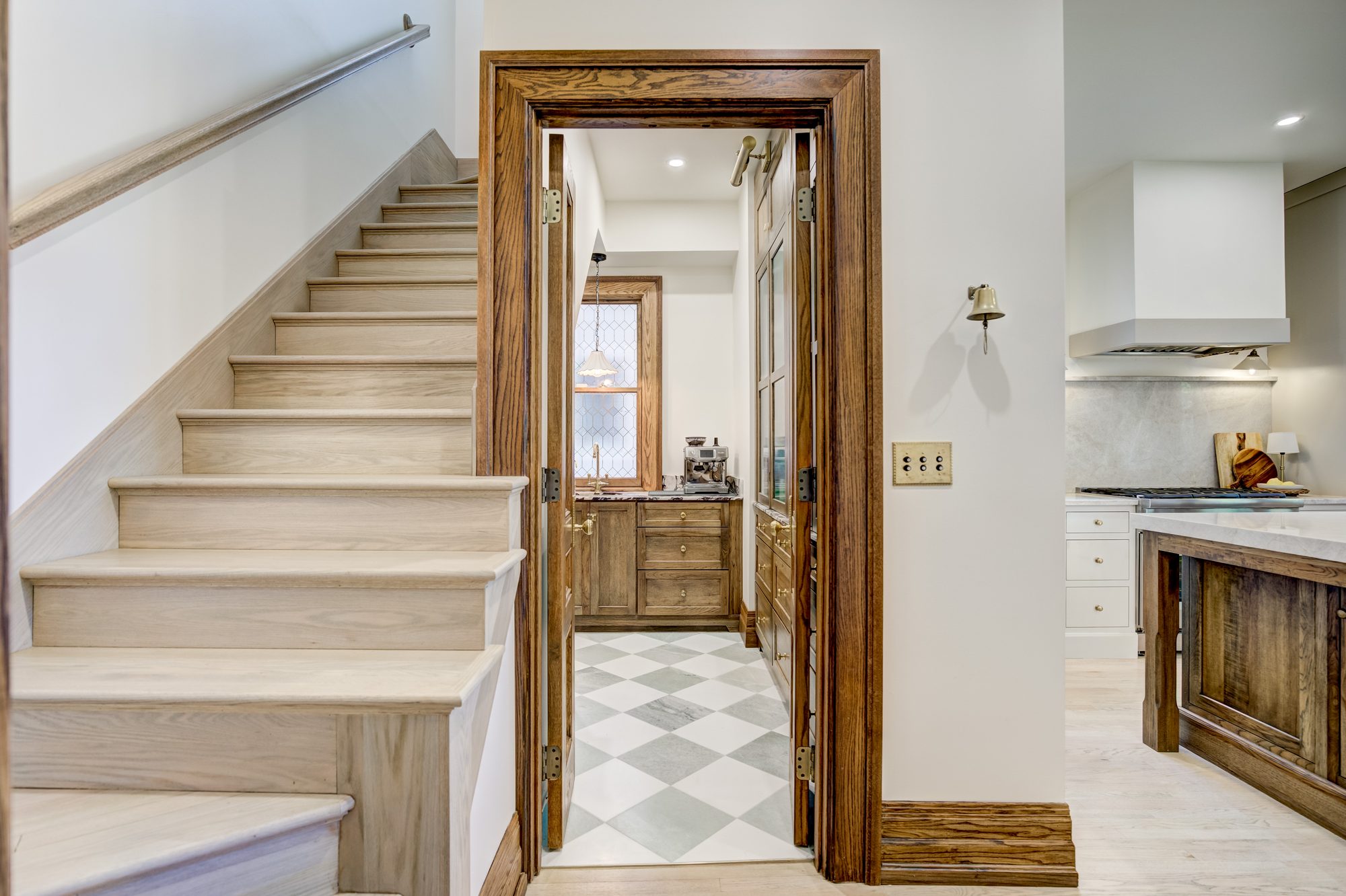View from the restored stair through open oak doors into the butler pantry in a Birmingham MI home remodel