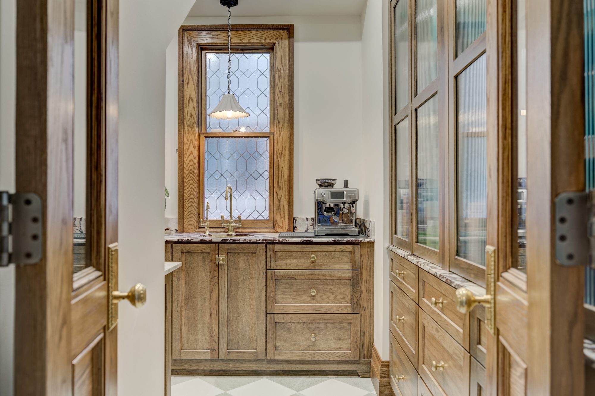 Butler pantry with Calacatta Viola marble counters, reeded glass cabinets and a leaded glass window in Birmingham MI