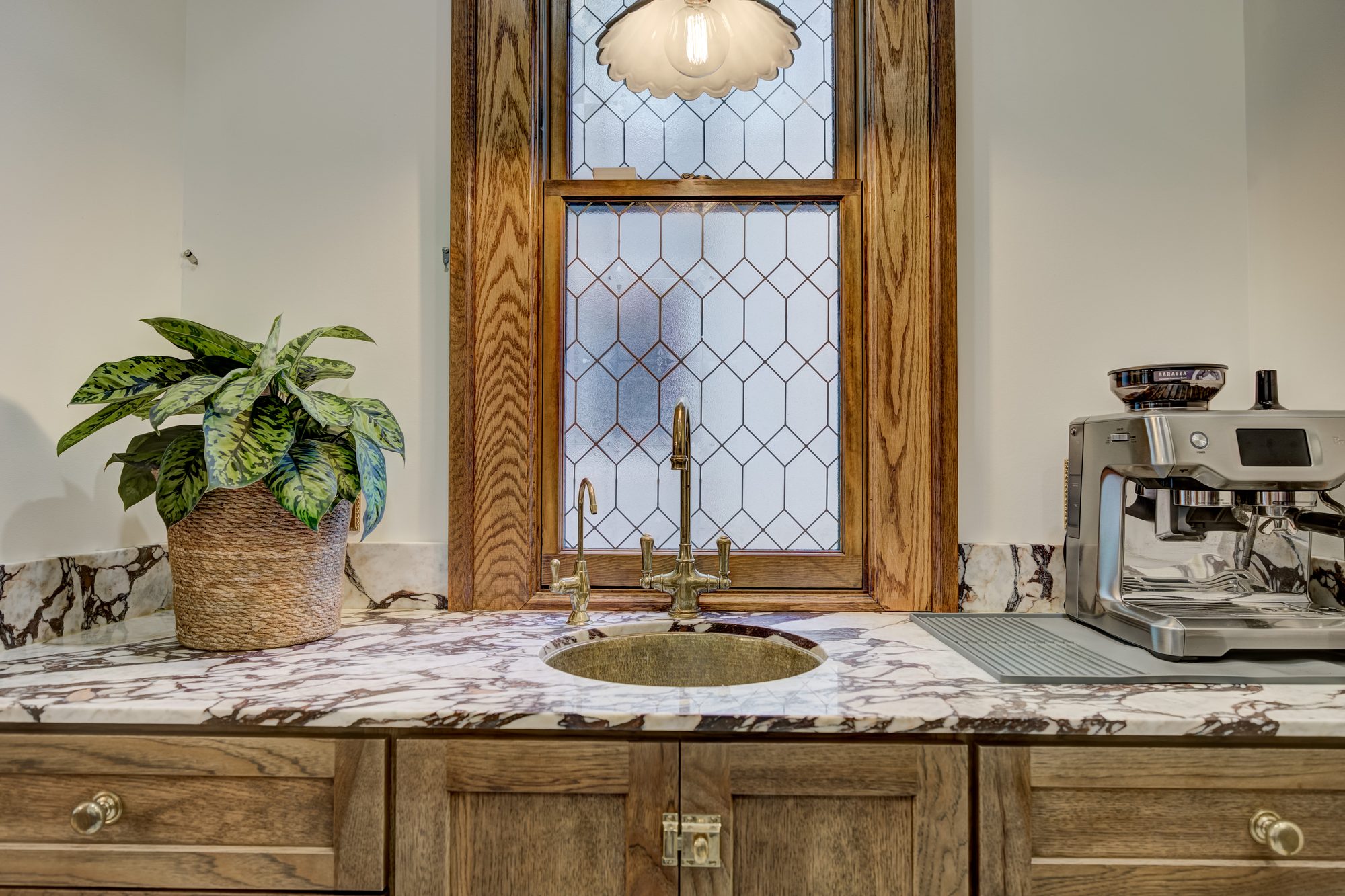 Hammered brass bar sink below a restored leaded glass window with Calacatta Viola marble in a Birmingham MI pantry
