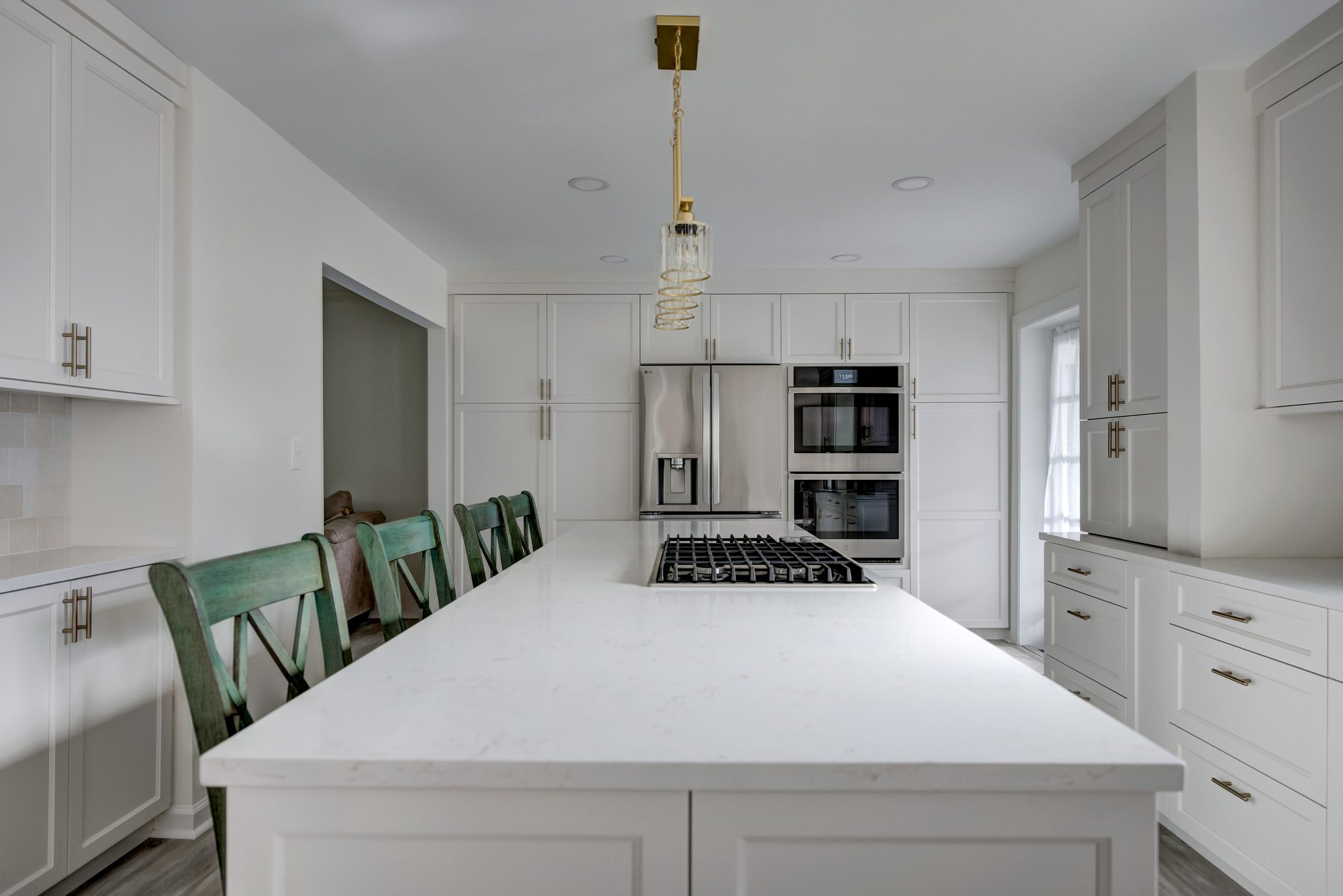 Quartz island looking toward the built in refrigerator and double wall ovens in a Beverly Hills MI kitchen remodel