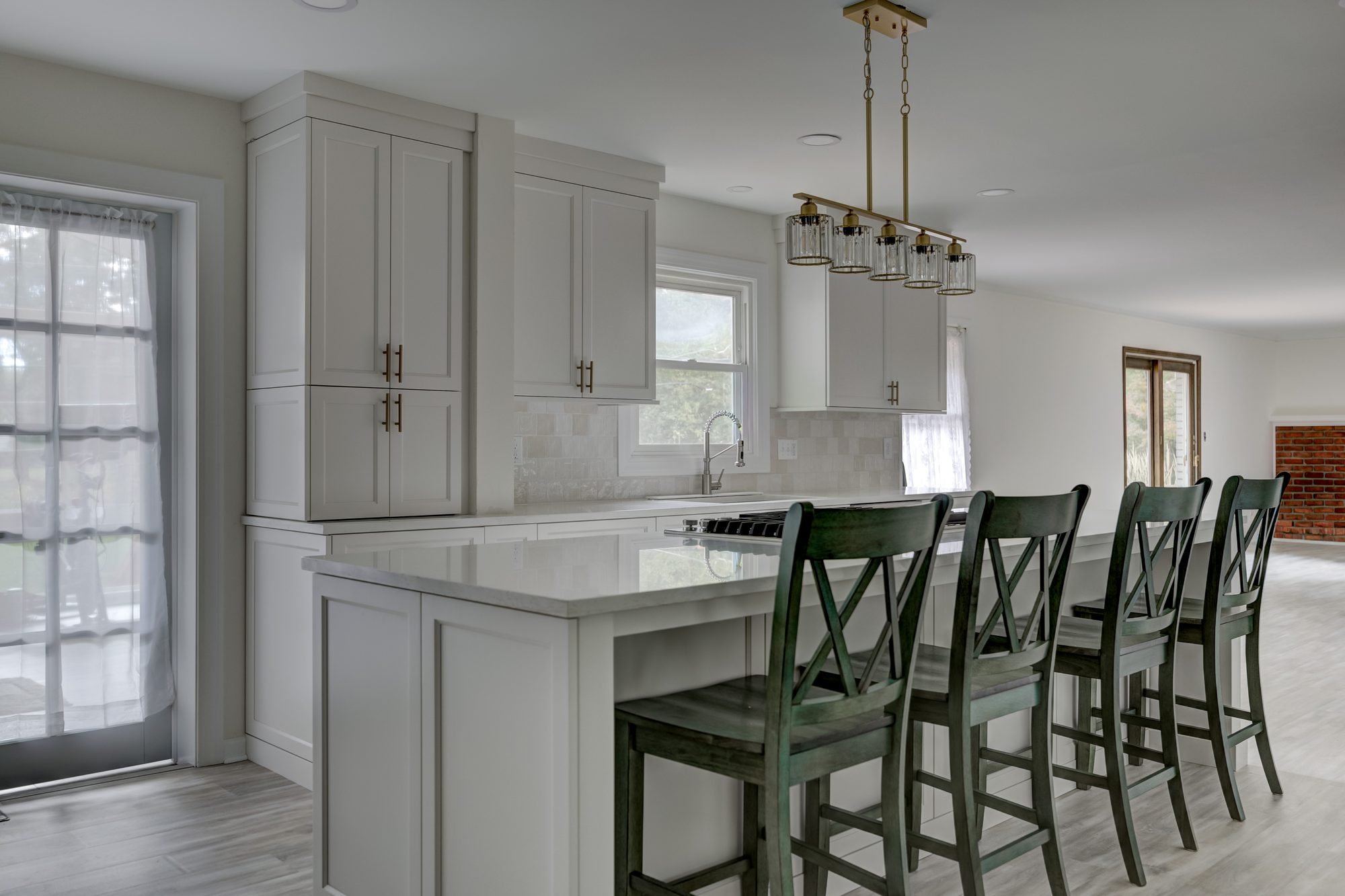 Island seating with counter stools under a brass linear chandelier in a Beverly Hills MI kitchen remodel