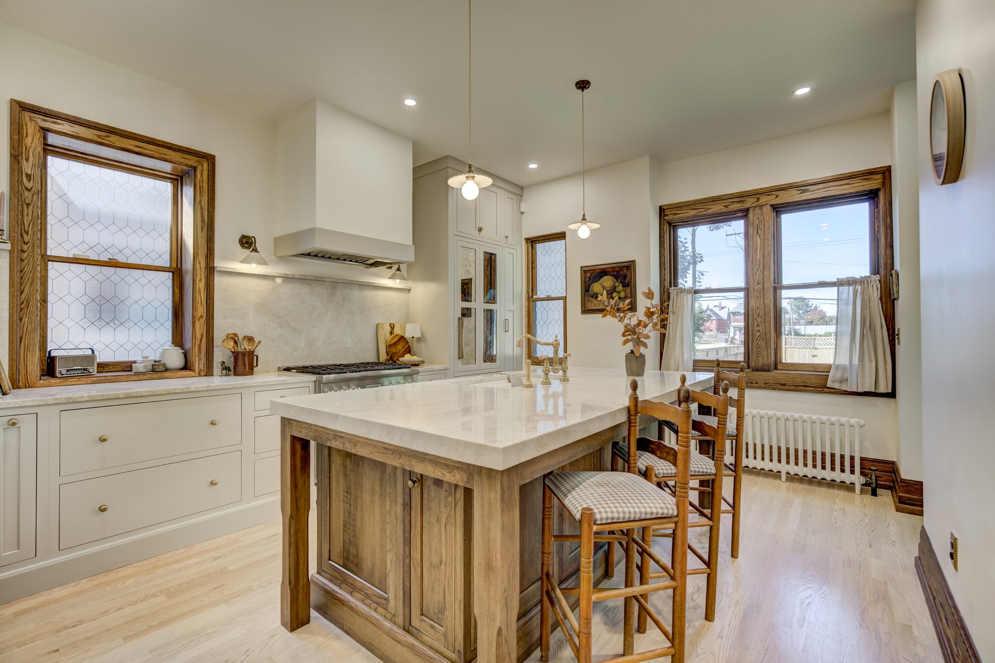 Remodeled Birmingham MI kitchen with a white oak island, marble counters, custom hood and original leaded glass windows