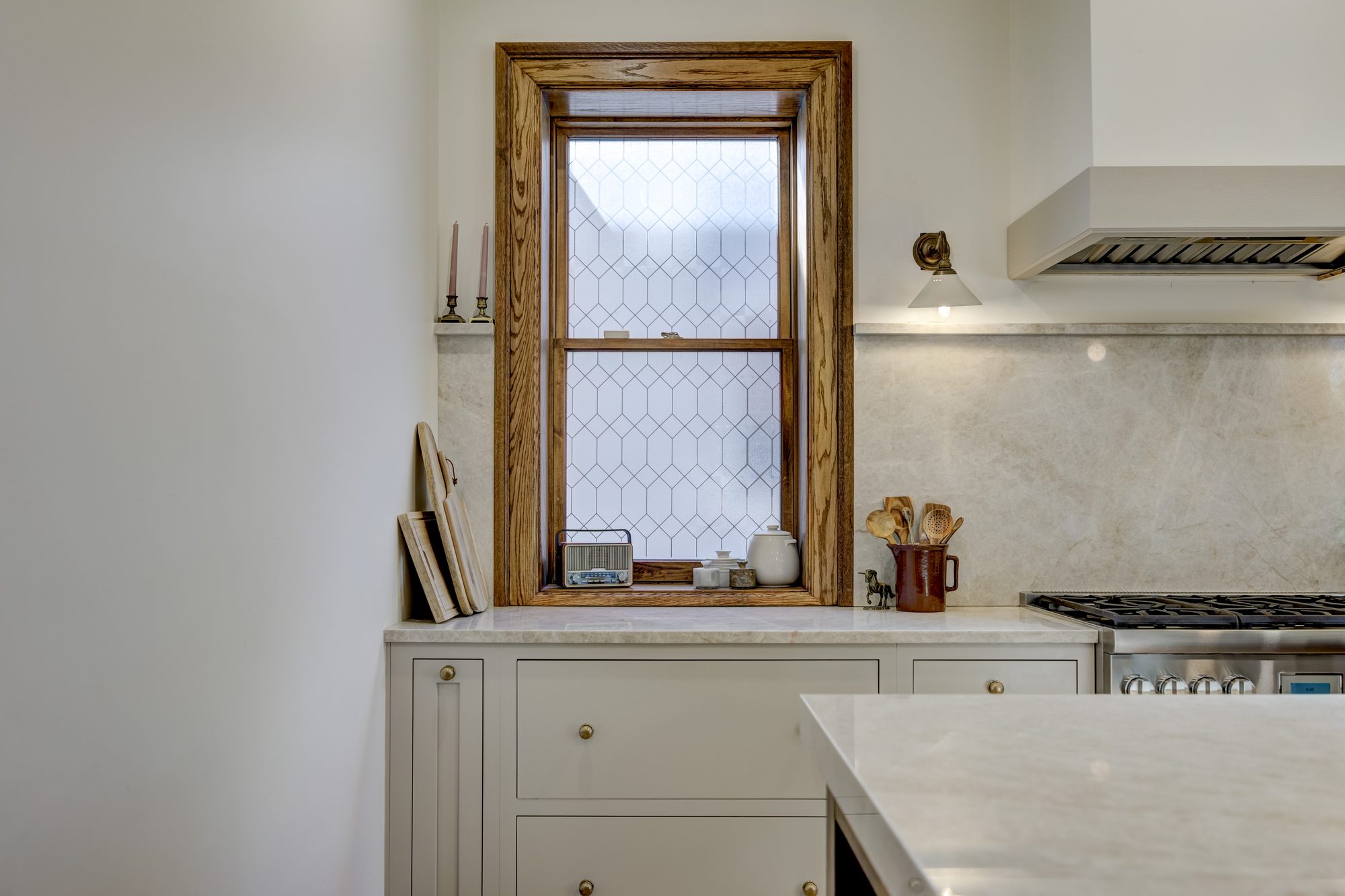 Restored original leaded glass window above the counter with a full slab marble backsplash in a Birmingham MI kitchen