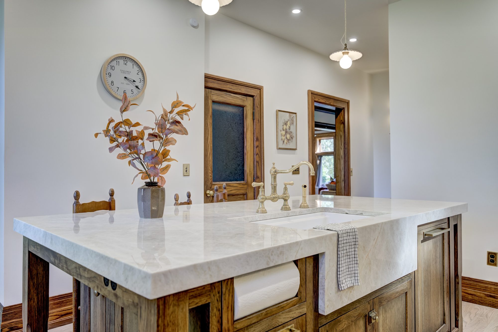 Island sink detail with unlacquered brass fittings and a marble counter in a Birmingham MI kitchen remodel