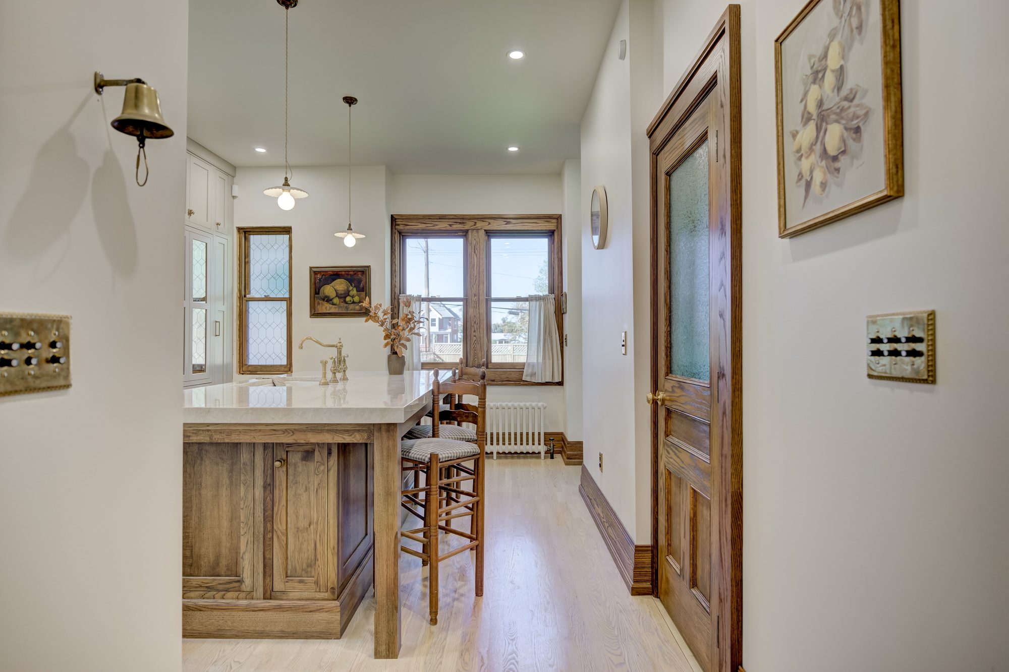 Hall view into the kitchen with the original brass servant bell and push button switch plates in a Birmingham MI home