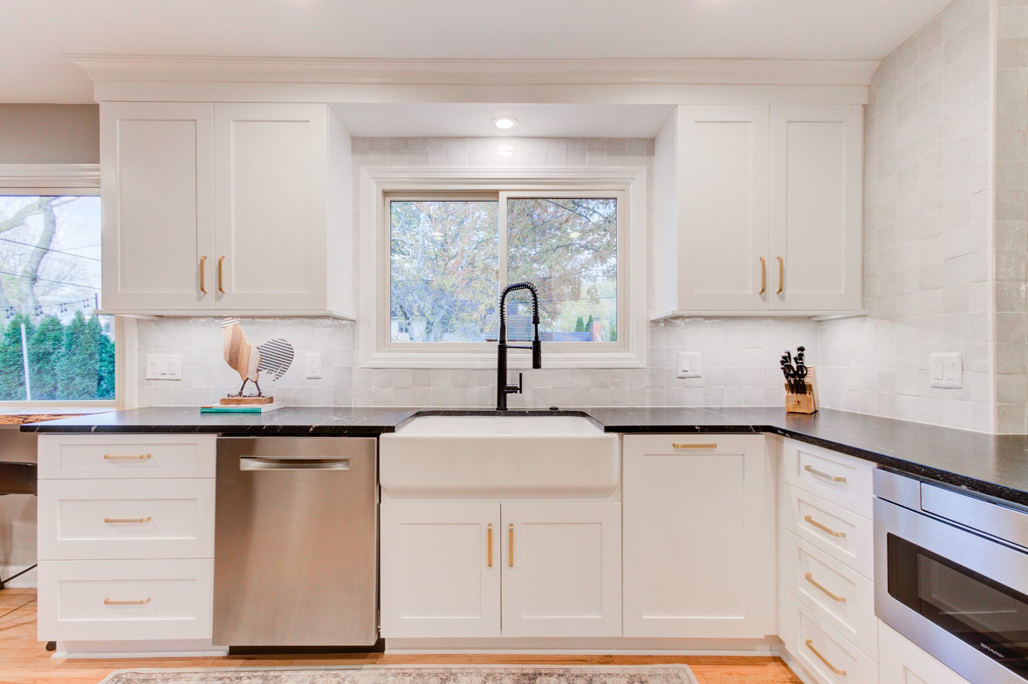 Fireclay apron front sink below the window with a white zellige backsplash in a Bloomfield Hills MI kitchen remodel
