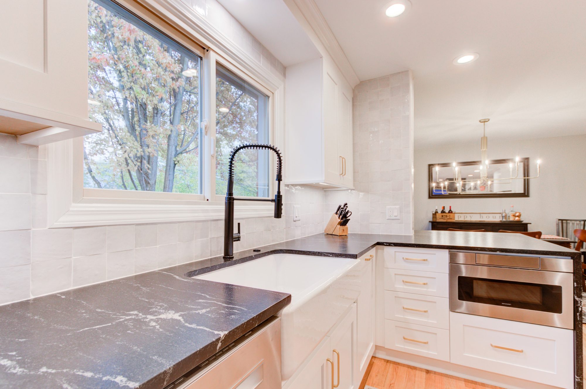 Apron sink and honed black granite counters looking through to the dining room in a Bloomfield Hills MI kitchen