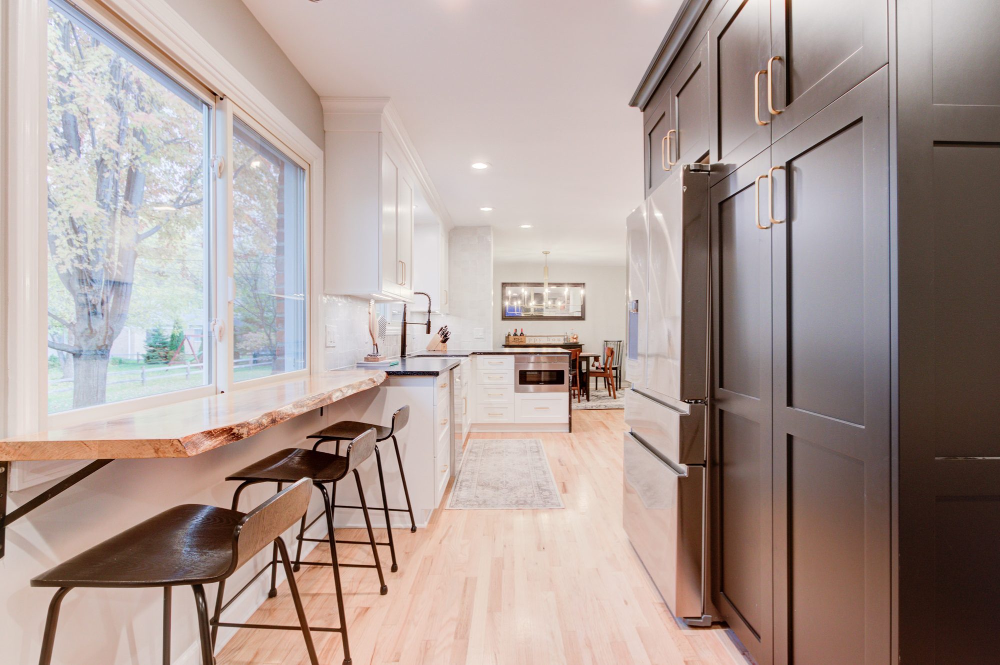 Live edge wood bar at the window beside a floor to ceiling pantry and refrigerator wall in a Bloomfield Hills MI kitchen
