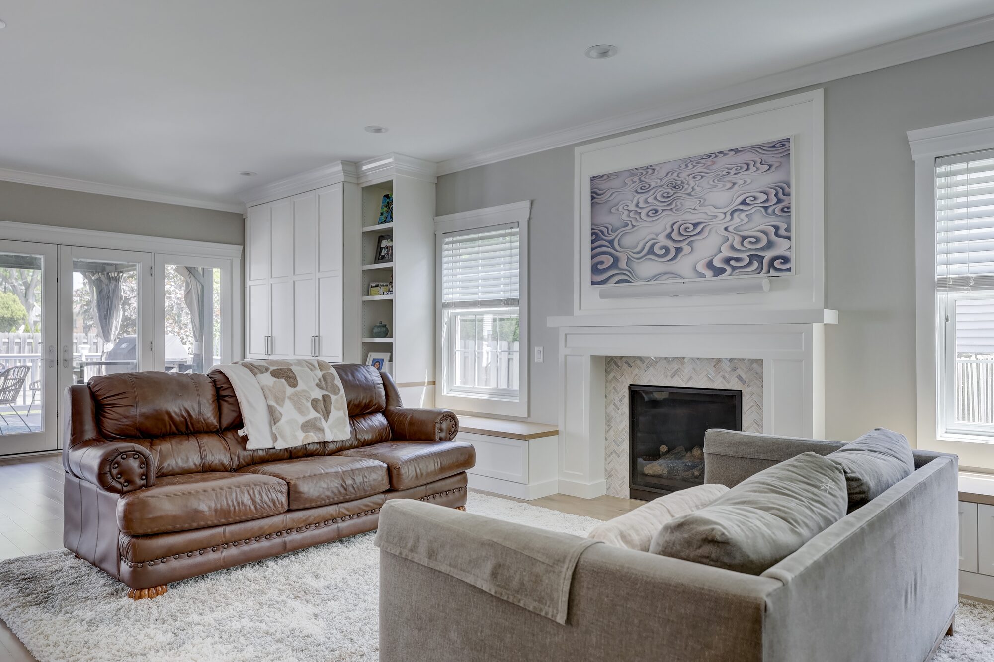 Family room addition in Birmingham, Michigan, with a custom fireplace surround, built-in cabinetry and French doors to the deck, by Maxwell Building Services