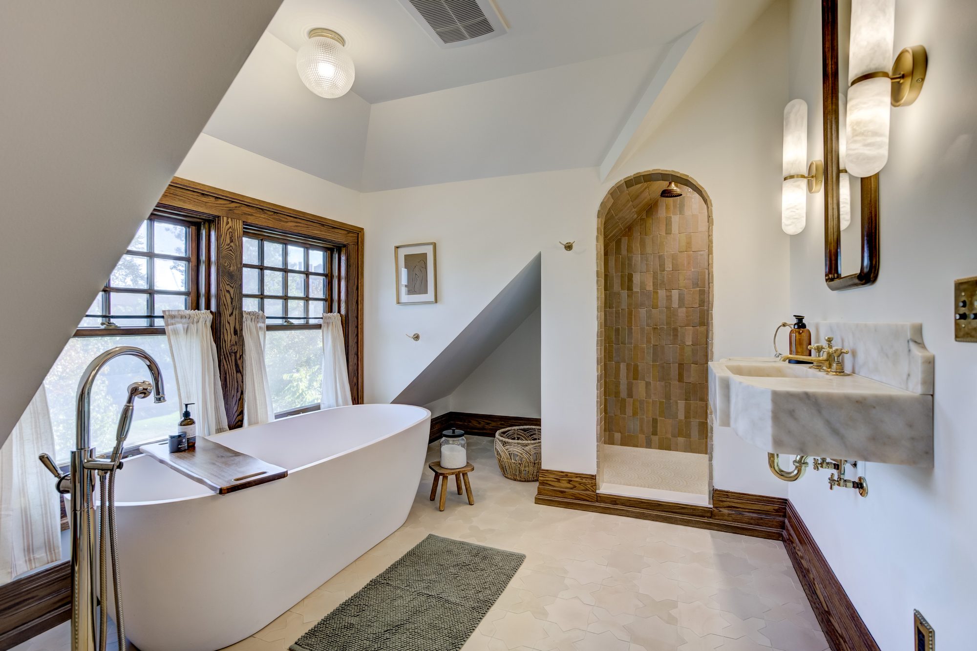 Soaking tub looking toward the arched tile shower and antique marble sink in a Birmingham MI master bathroom