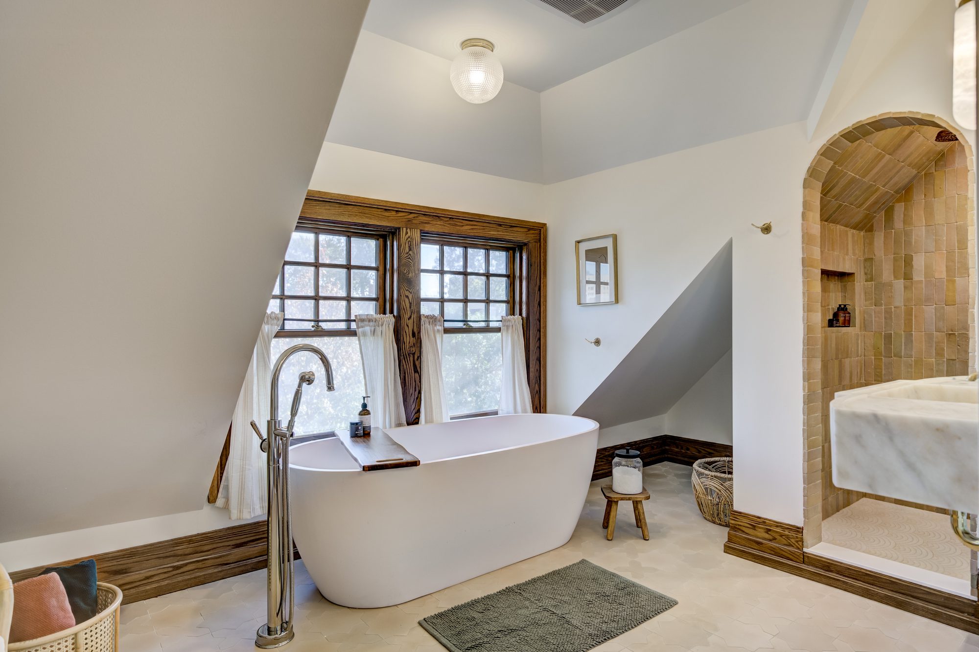 Freestanding soaking tub set under the dormer window with restored oak trim in a Birmingham MI master bathroom
