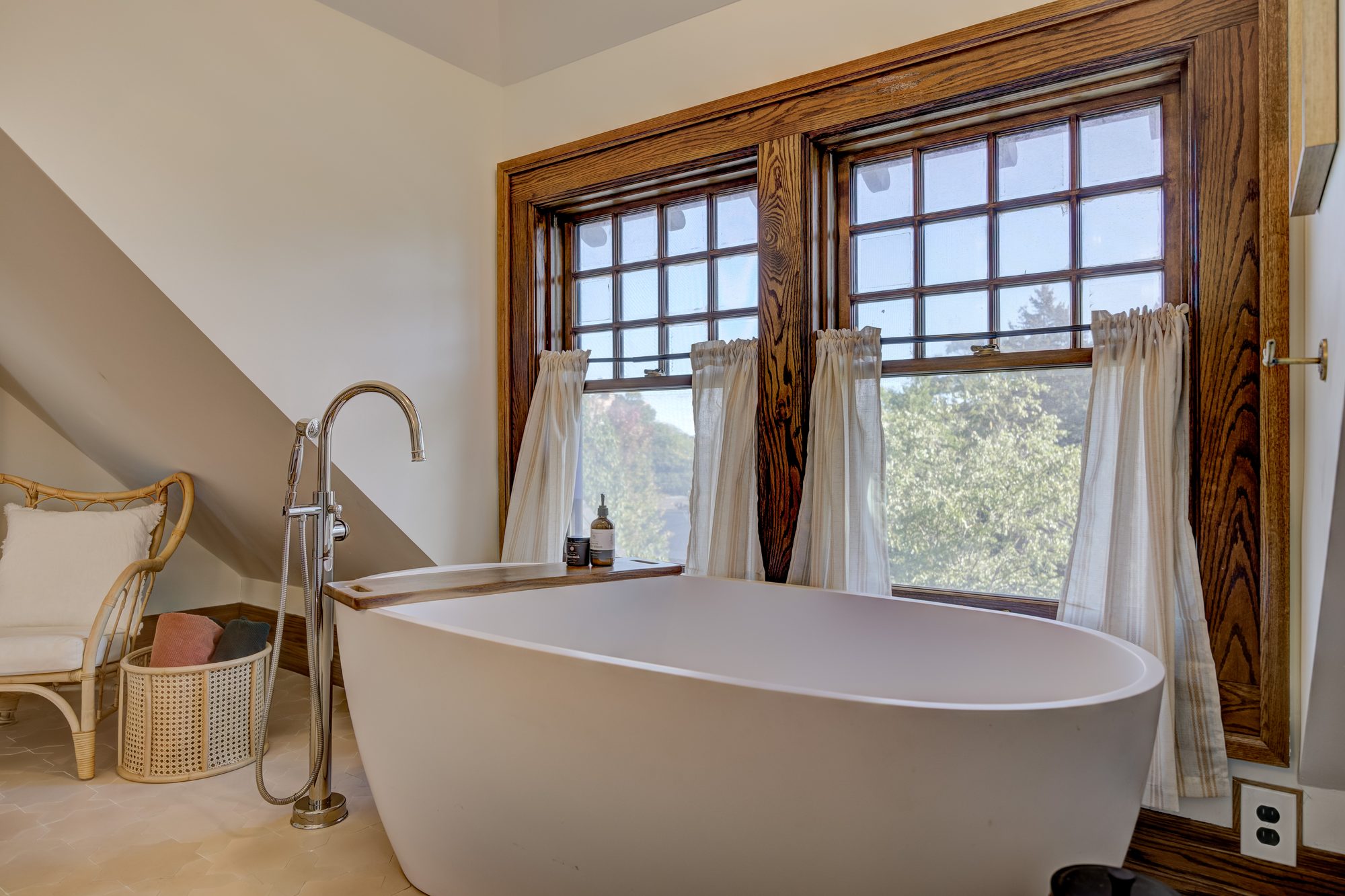 Soaking tub and polished nickel floor mount filler beside restored original oak window trim in Birmingham MI