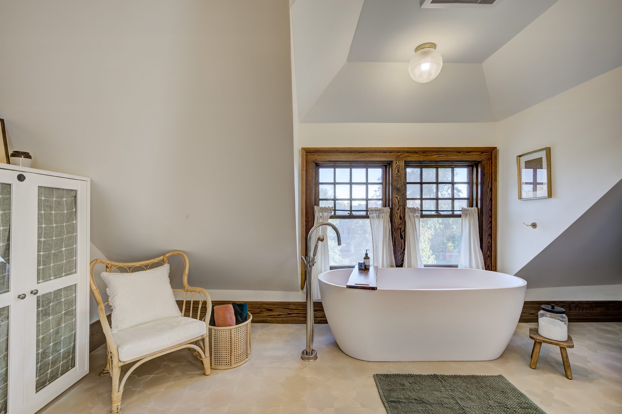 Soaking tub and seating area tucked under the sloped ceiling in a Birmingham MI master bathroom remodel