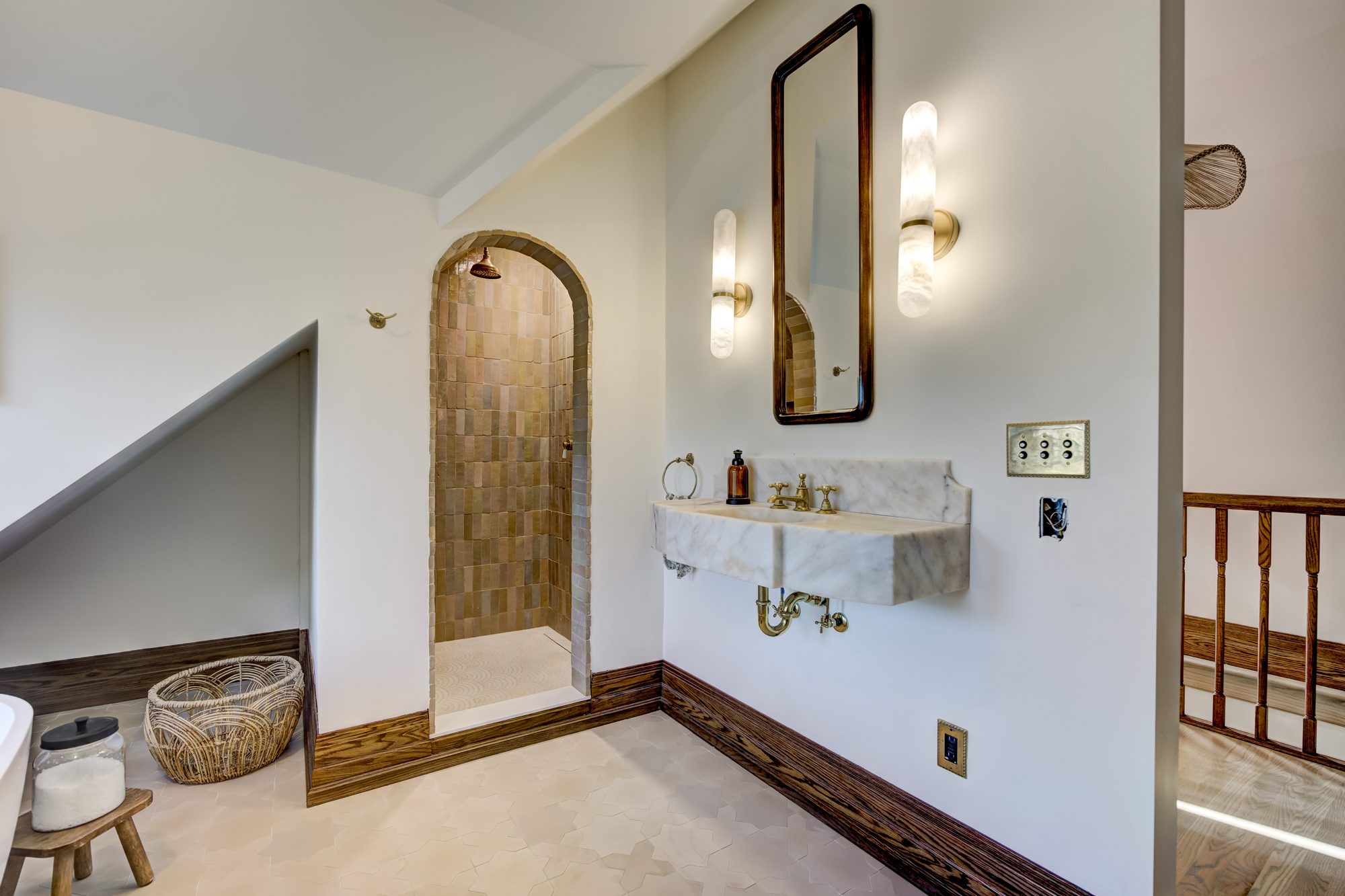 Antique marble wall mount sink with alabaster sconces and a wood framed mirror in a Birmingham MI master bathroom
