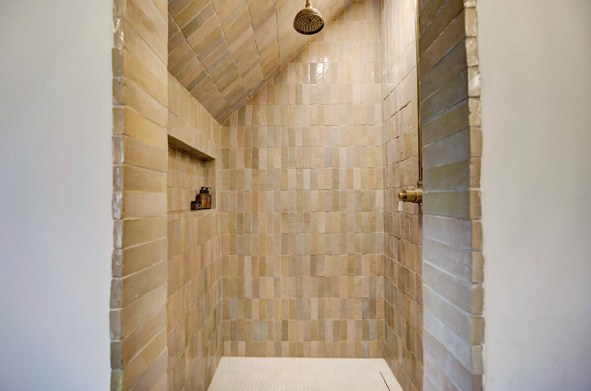 Inside the zellige tile shower, tile carried up the sloped ceiling with a built in niche in a Birmingham MI bathroom