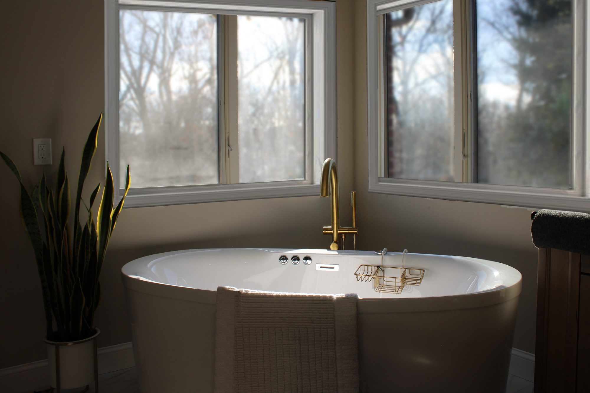 Freestanding tub set into corner windows with a wooded view in a Rochester Hills MI master bathroom remodel